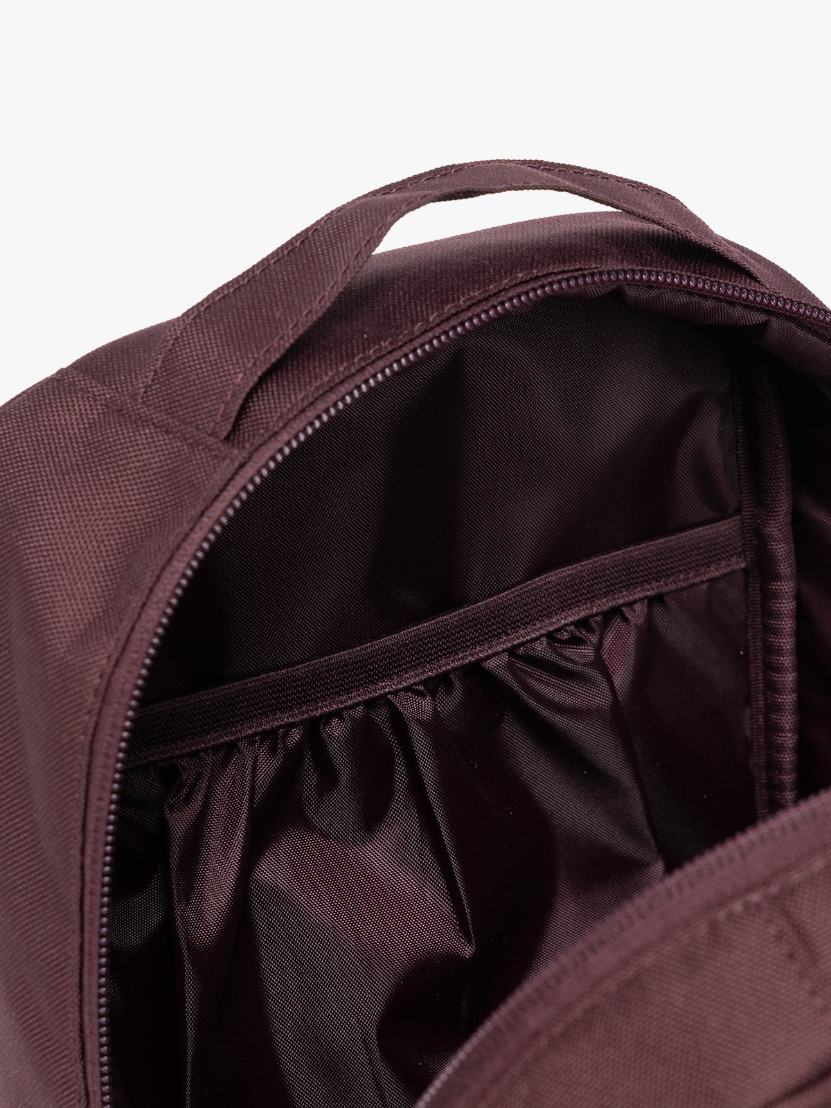 Closeup of the inner compartments of Dark burgundy Dark Cherry color of the CALPAK Everything Cube organizer with a top handle, a front zippered pocket, and a textured mesh lower panel, shown against a plain white background; ACE2401-DARK-CHERRY