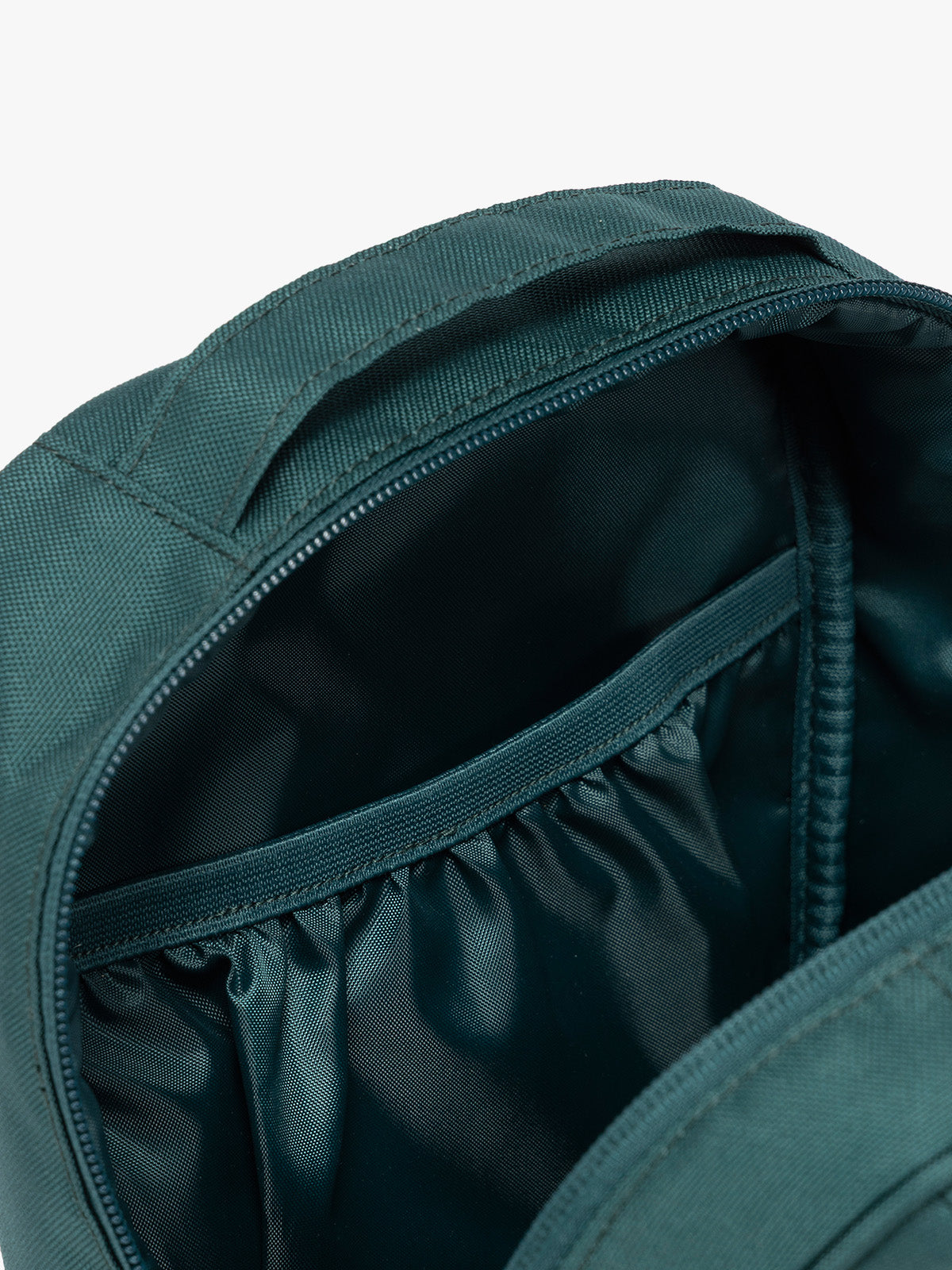 Close up of inside compartment of the dark teal green Kale CALPAK Everything Cube organizer with a top handle, a front zippered pocket, and a textured mesh lower panel, shown against a plain white background; ACE2401-KALE