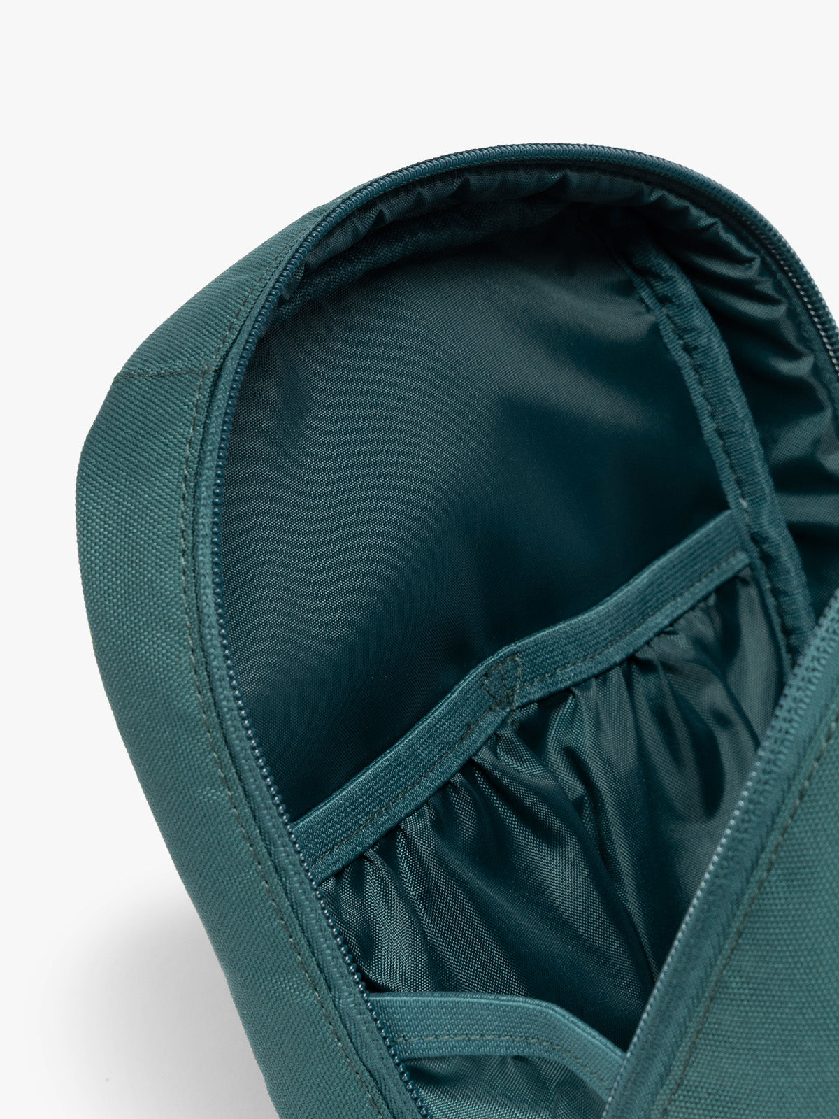 Close up of compartments in the dark teal green Kale CALPAK Everything Cube organizer with a top handle, a front zippered pocket, and a textured mesh lower panel, shown against a plain white background; ACE2401-KALE