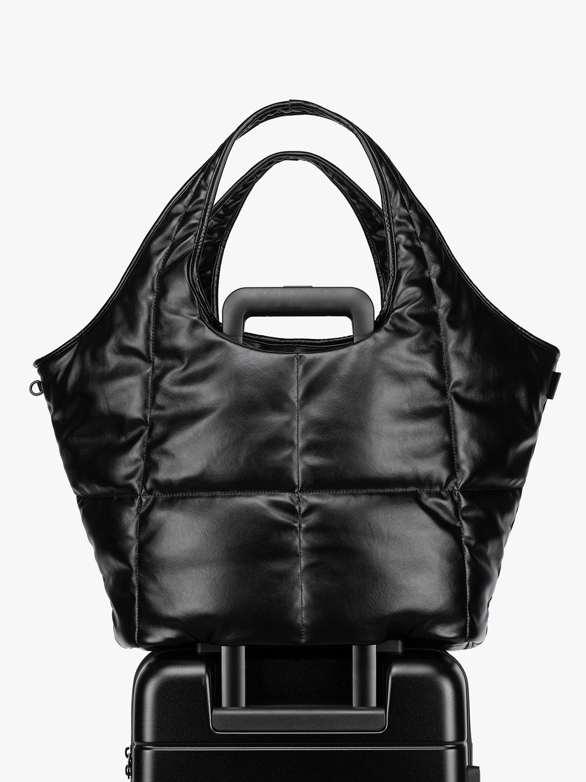 Luggage trolley sleeve feature of the Black quilted puffer CALPAK Luka Everything Tote Bag with a smooth finish and double shoulder straps, shown against a plain white background; AET2601-BLACK-PU