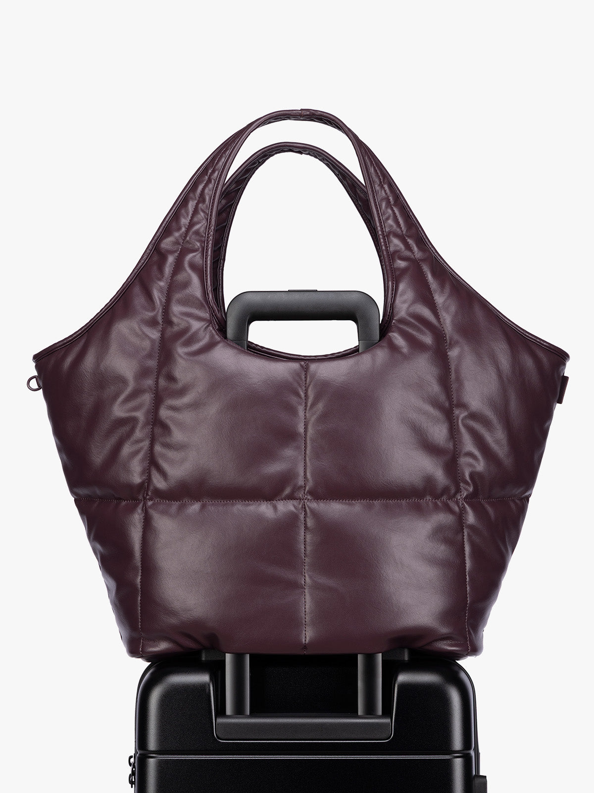 Luggage trolley sleeve of the Dark Cherry quilted puffer CALPAK Luka Everything Tote Bag with a smooth finish and double shoulder straps, shown against a plain white background; AET2601-DARK-CHERRY-PU