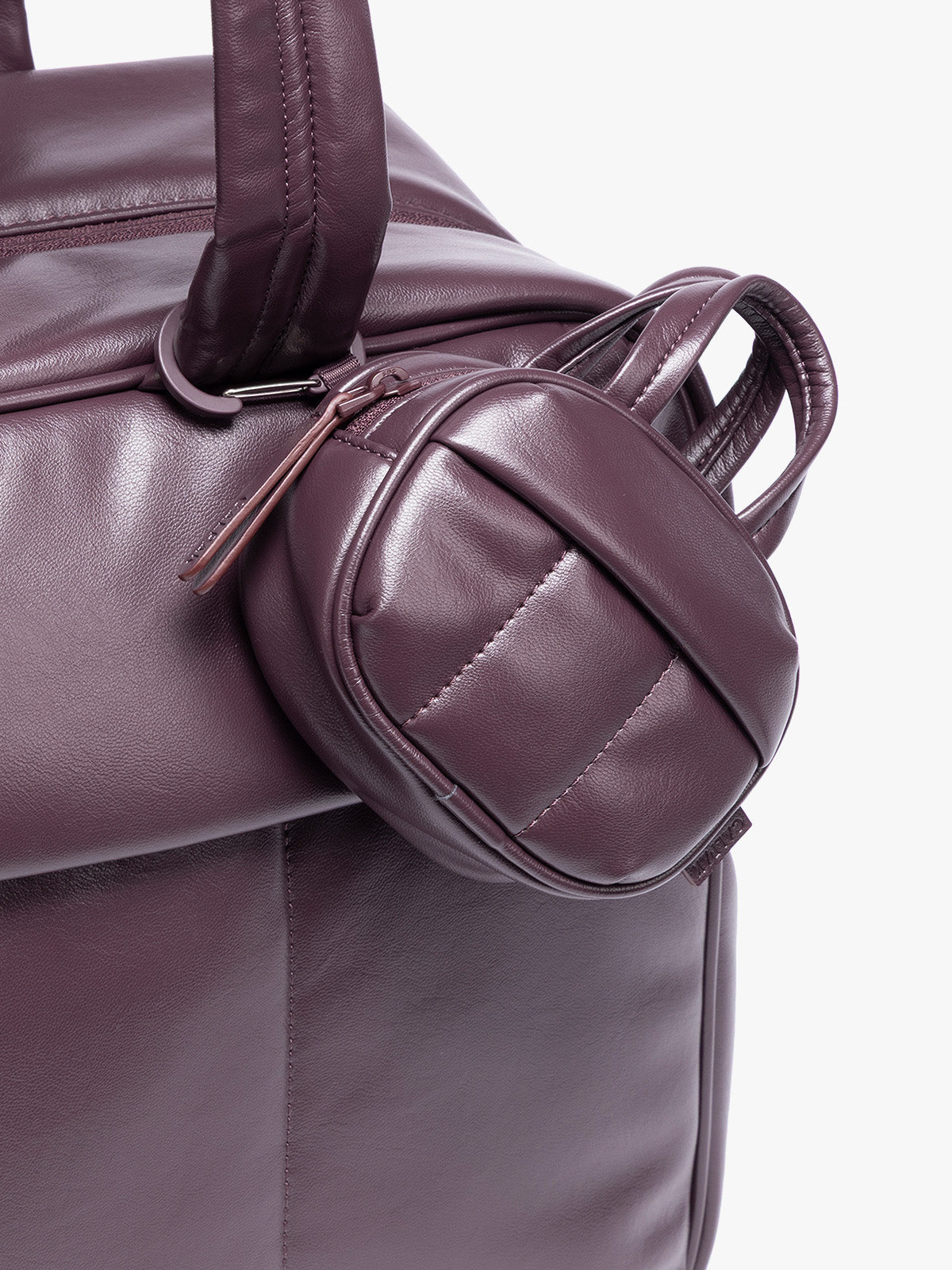 A close-up of a deep burgundy Dark Cherry vegan leather top-handle CALPAK Luka Zip Bag Charm with a zippered front pocket and a small side strap  with a matching small zippered pouch attached near the handle, shown against a clean white background; ALK2501-DARK-CHERRY-PU