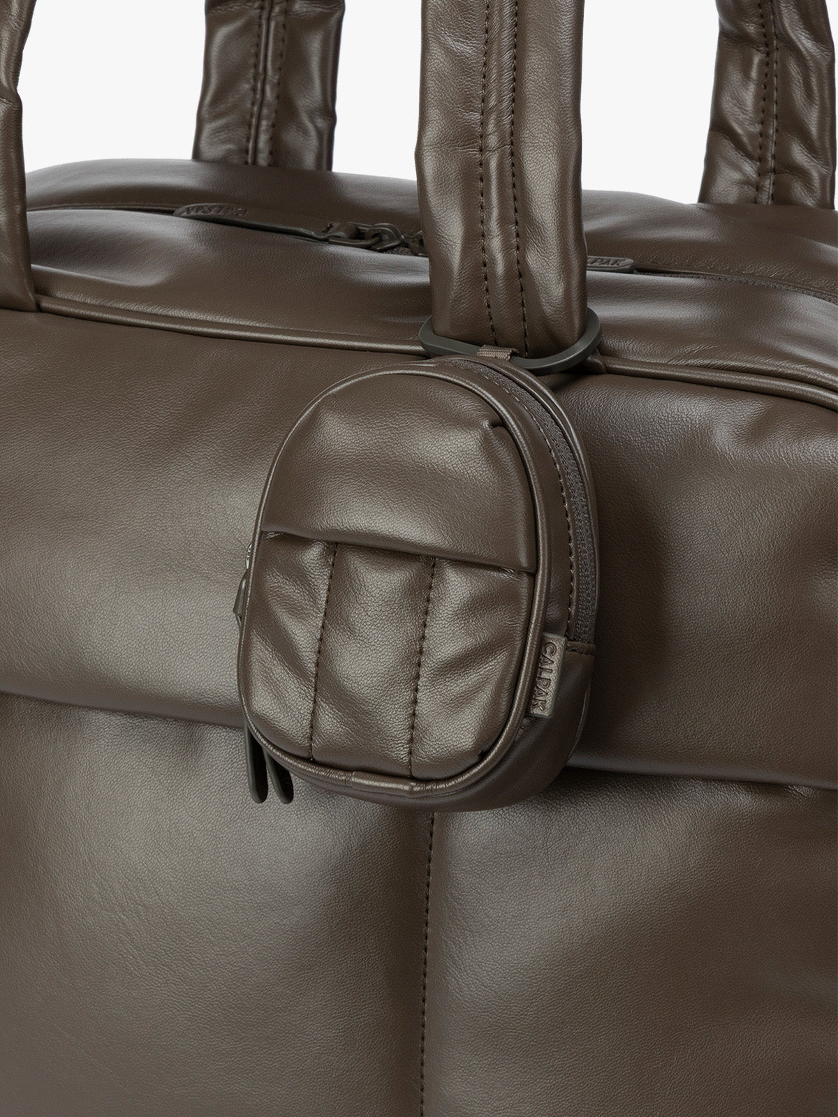 A close-up of dark brown Mushroom CALPAK Luka Backpack Zip Bag Charm leather backpack keychain featuring a matching bag shown on a plain white background; AMB2201-MUSHROOM-PU