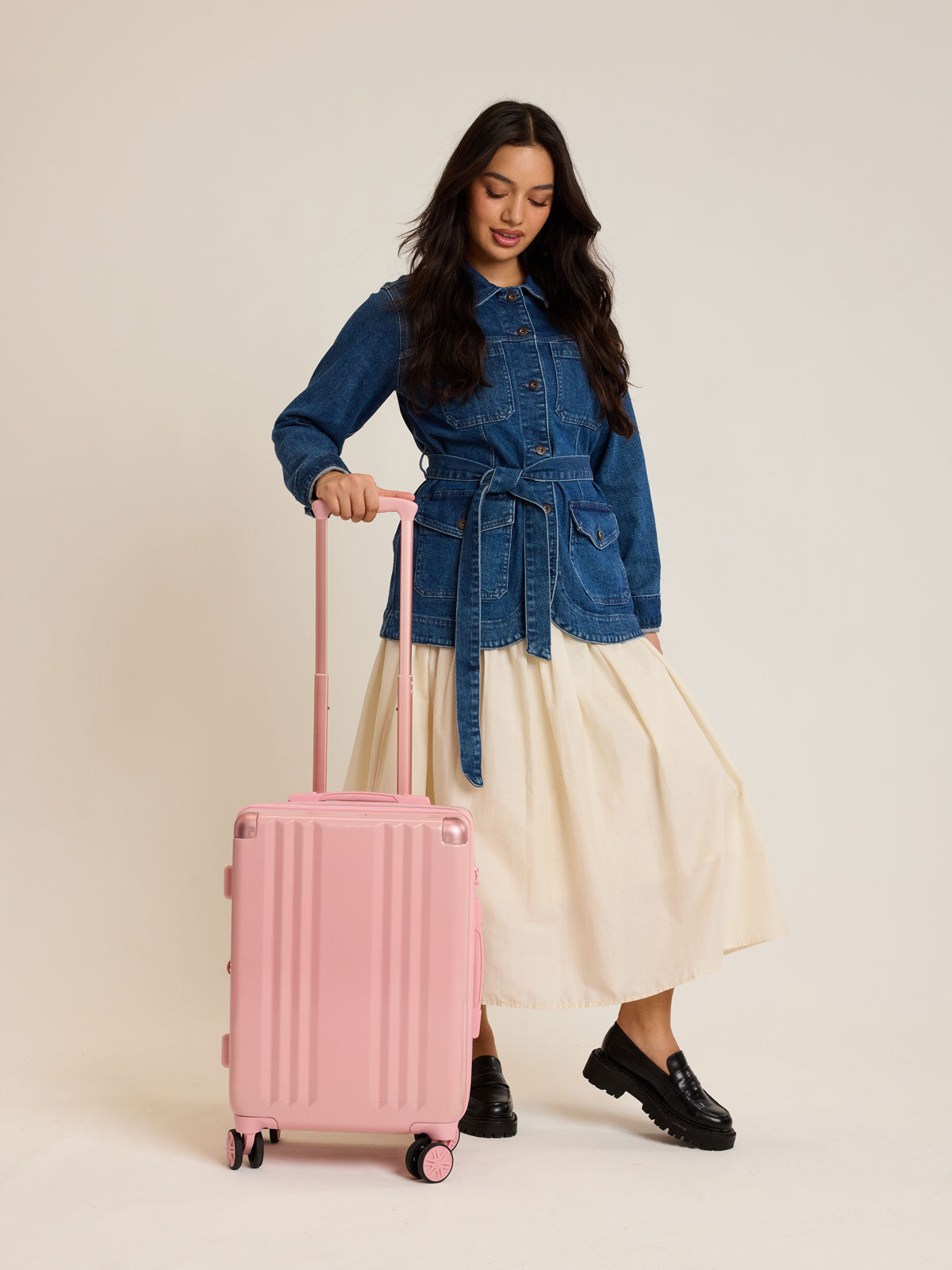 Model with CALPAK Ambeur Carry-On Luggage in metallic pink Blossom with pink wheels;  LAM1020-BLOSSOM