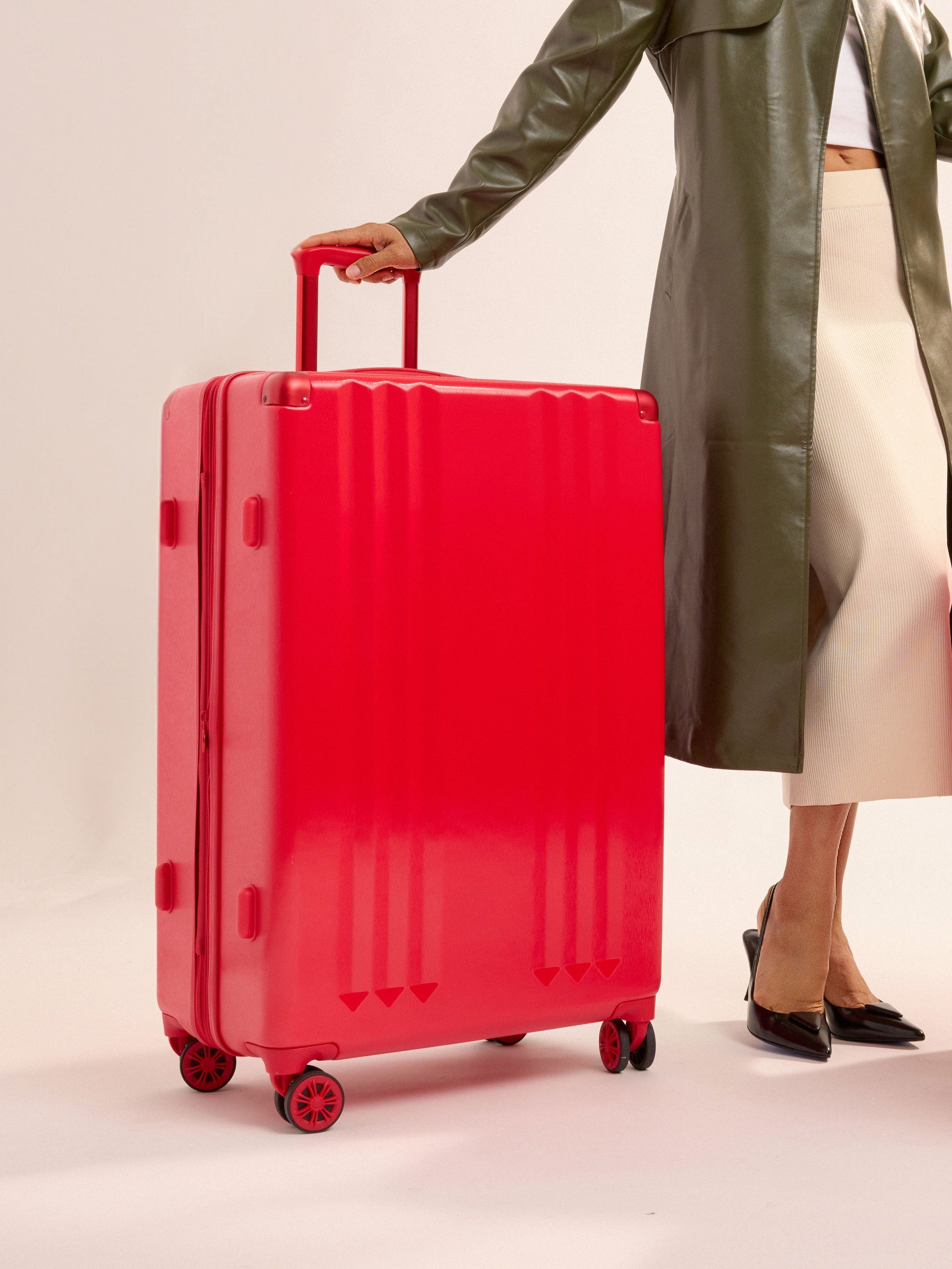 Model standing besides CALPAK Ambeur Large Luggage in metallic red; LAM1028-METALLIC-RED