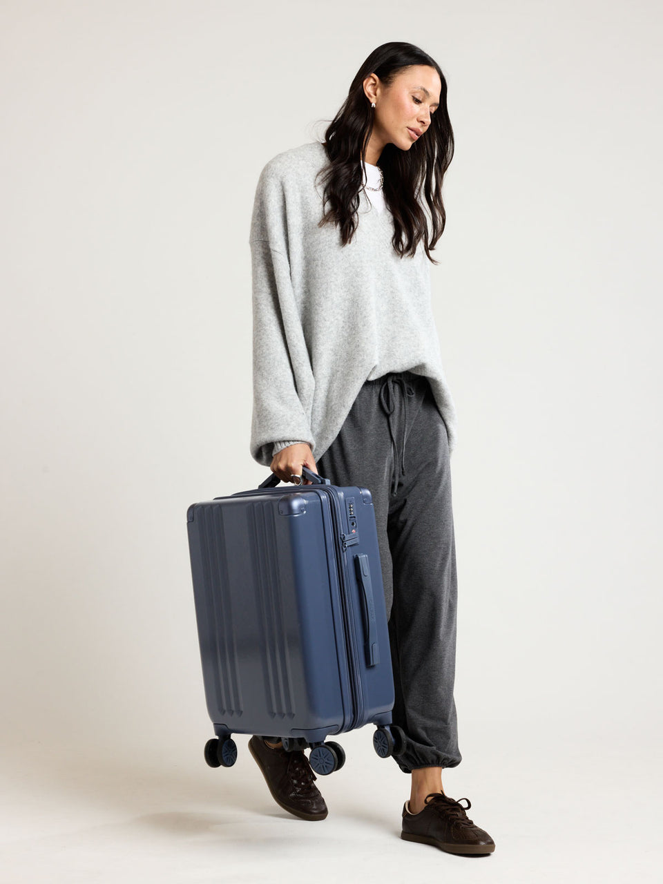 Model holding CALPAK Ambeur Carry On Luggage in dark blue metallic Indigo; LAM1020-INDIGO