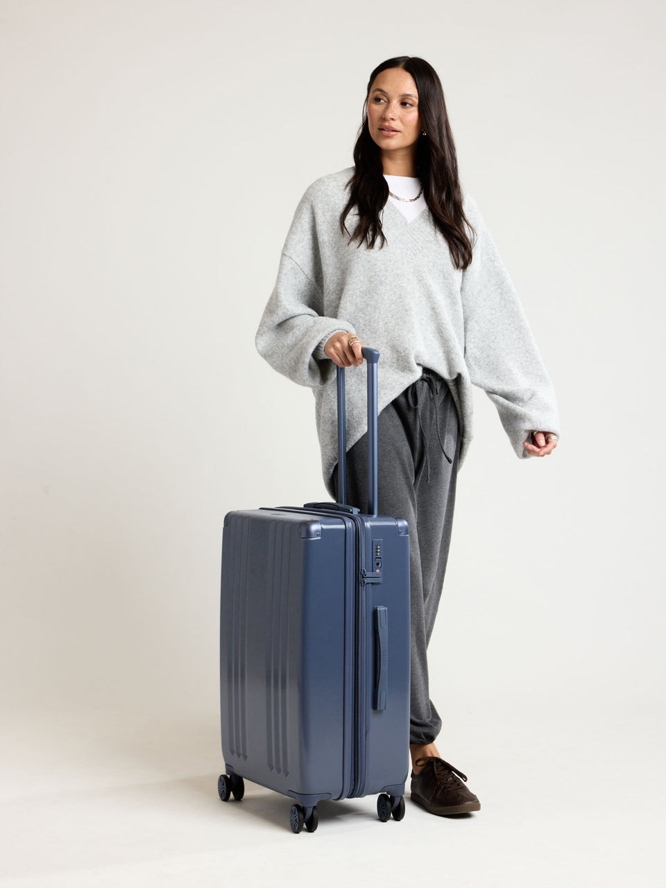 Model with CALPAK Ambeur Medium Luggage in dark blue metallic Indigo; LAM1024-INDIGO