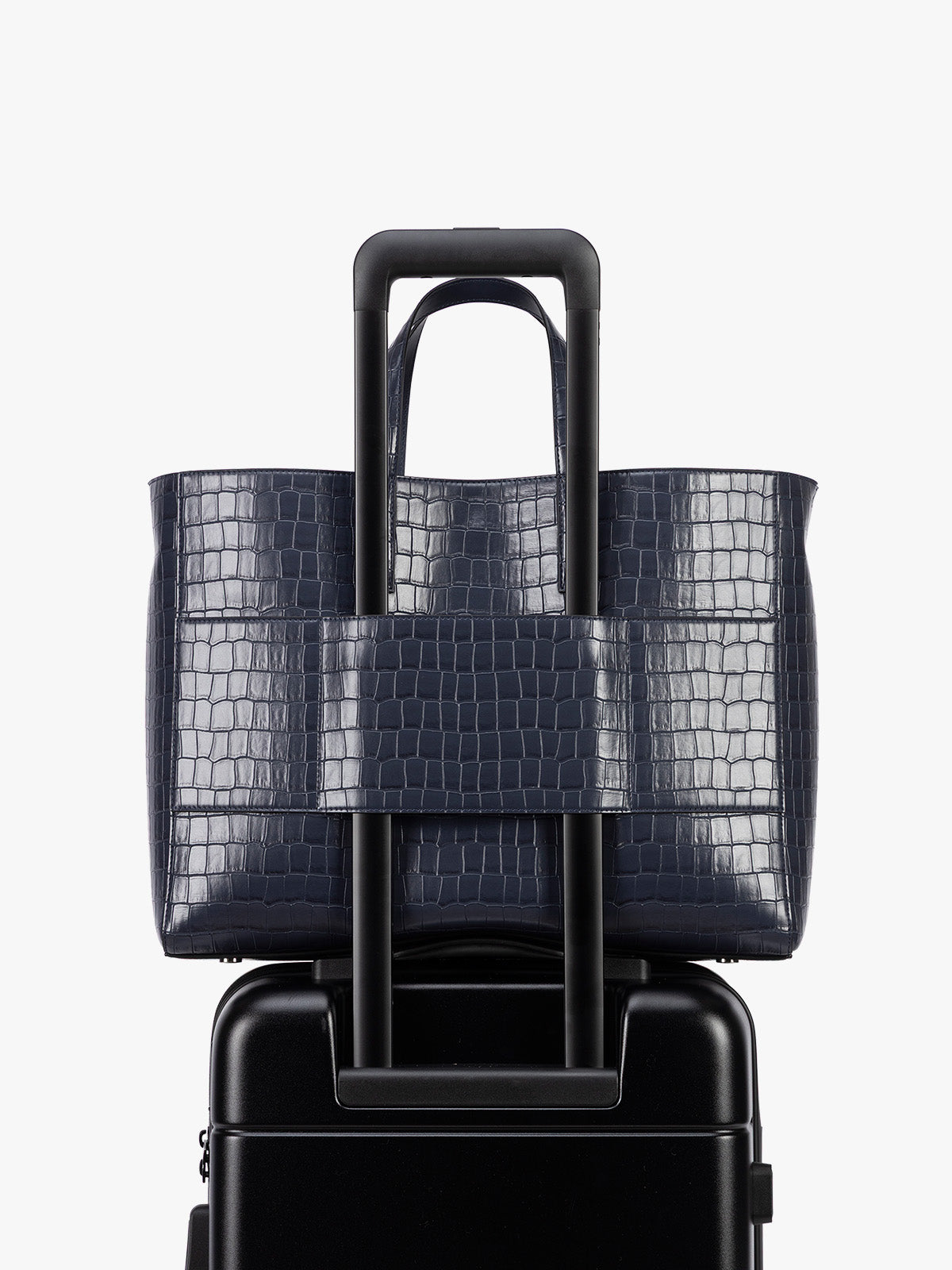 Backside luggage torlley sleeve of CALPAK Haven 16" Laptop Tote in blue Navy crocodile-embossed tote bag with top handles and a detachable shoulder strap, shown against a plain white background; ATO2102-NAVY-FAUX-CROC