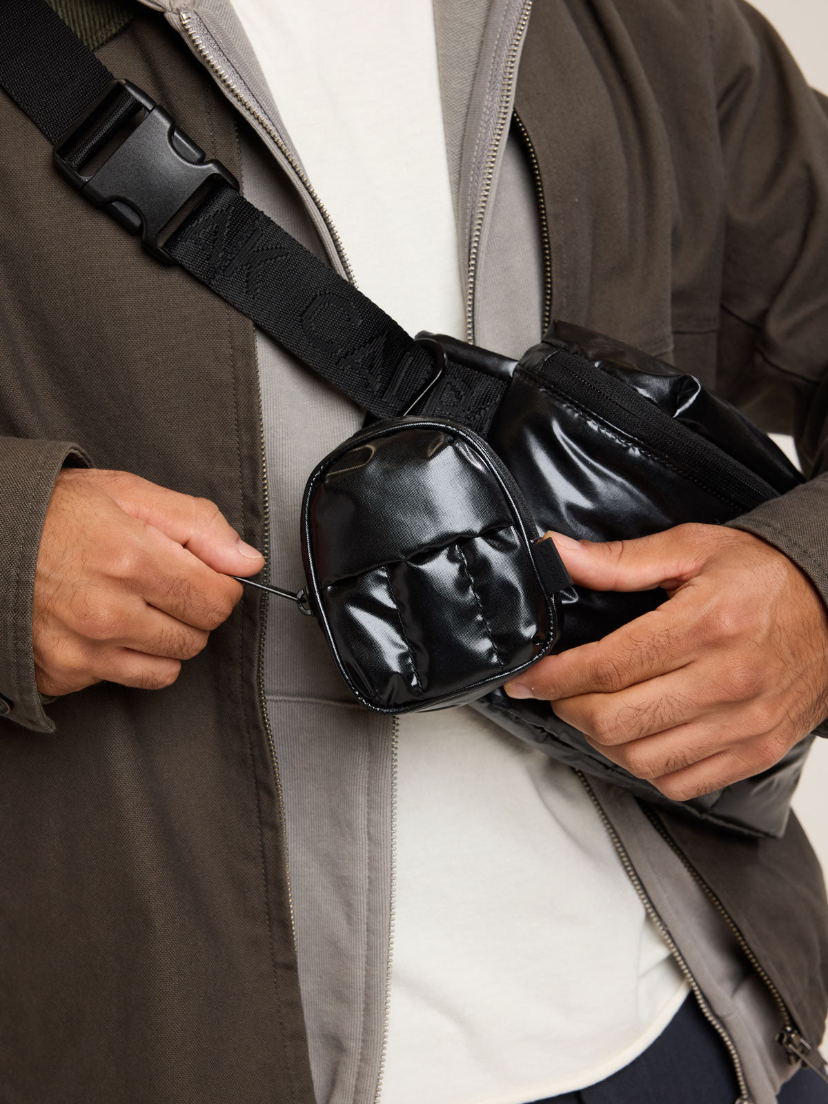 Model with CALPAK Luka Backpack Key Pouch in Glazed Black on a white background; AMB2201-GLAZED-BLACK