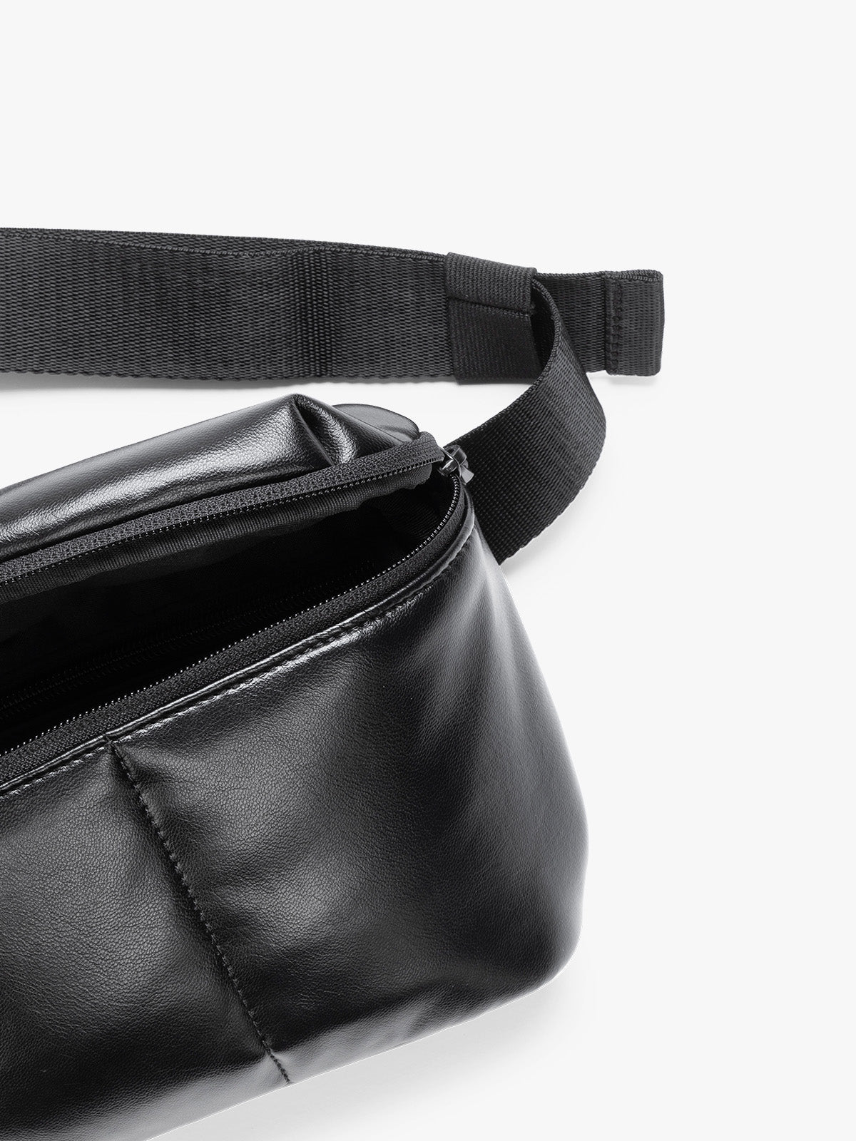 Close up of front zipper and crossbody strap of a black vegan leather CALPAK Luka Belt Bag with a zippered front pocket and side straps, shown against a plain white background; BB1901-BLACK-PU