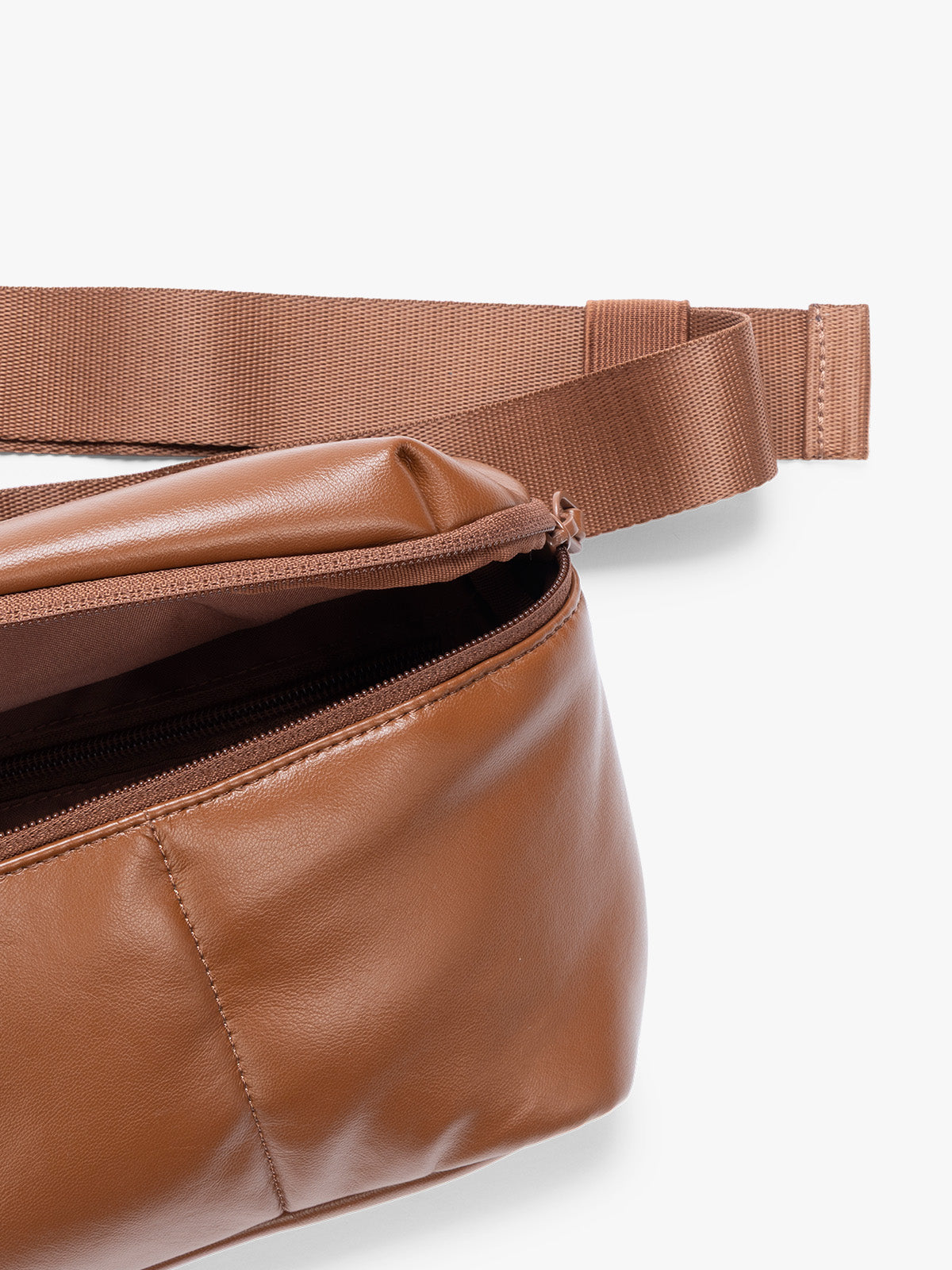 Closeup of front zippered pocket and crossbody strap of a light Honey Brown Mushroom vegan leather CALPAK Luka Belt Bag with a zippered front pocket and side straps, shown against a plain white background; BB1901-HONEY-BROWN-PU
