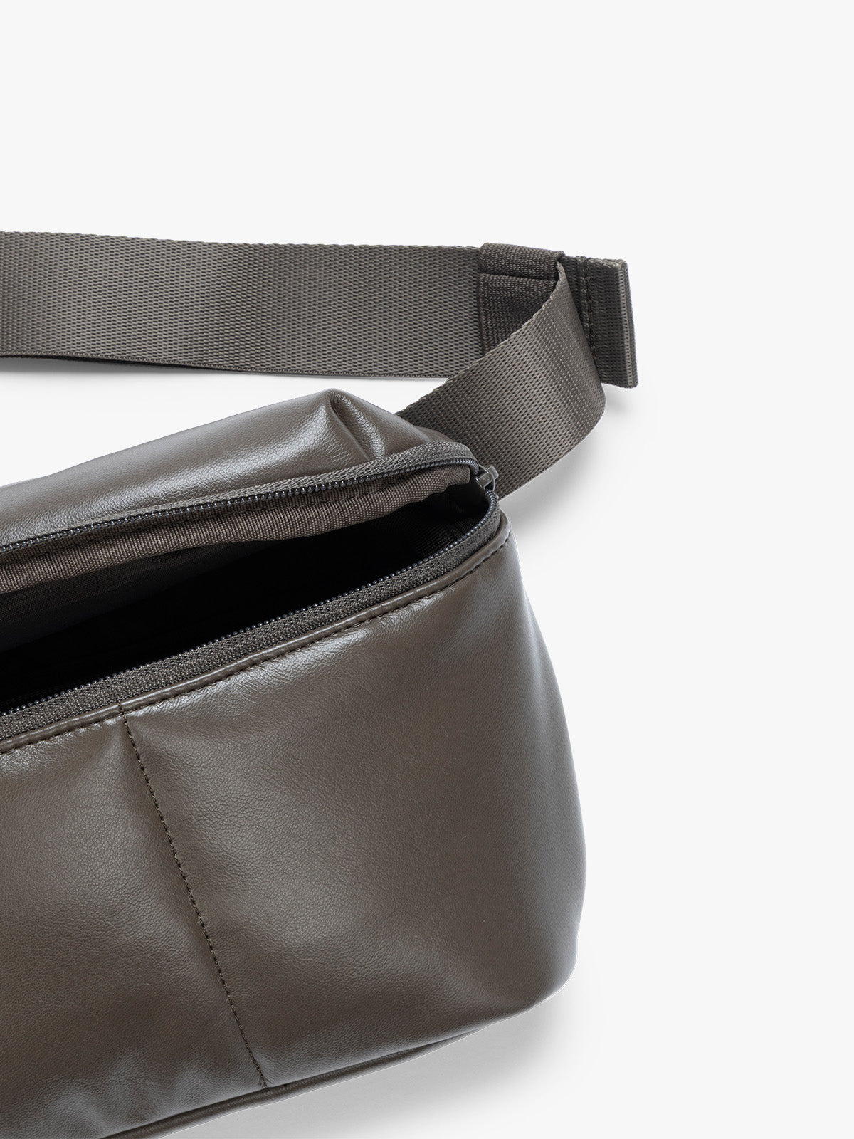 Close up of front pocket zipper and crossbody strap of a dark brown Mushroom vegan leather CALPAK Luka Belt Bag with a zippered front pocket and side straps, shown against a plain white background; BB1901-MUSHROOM-PU