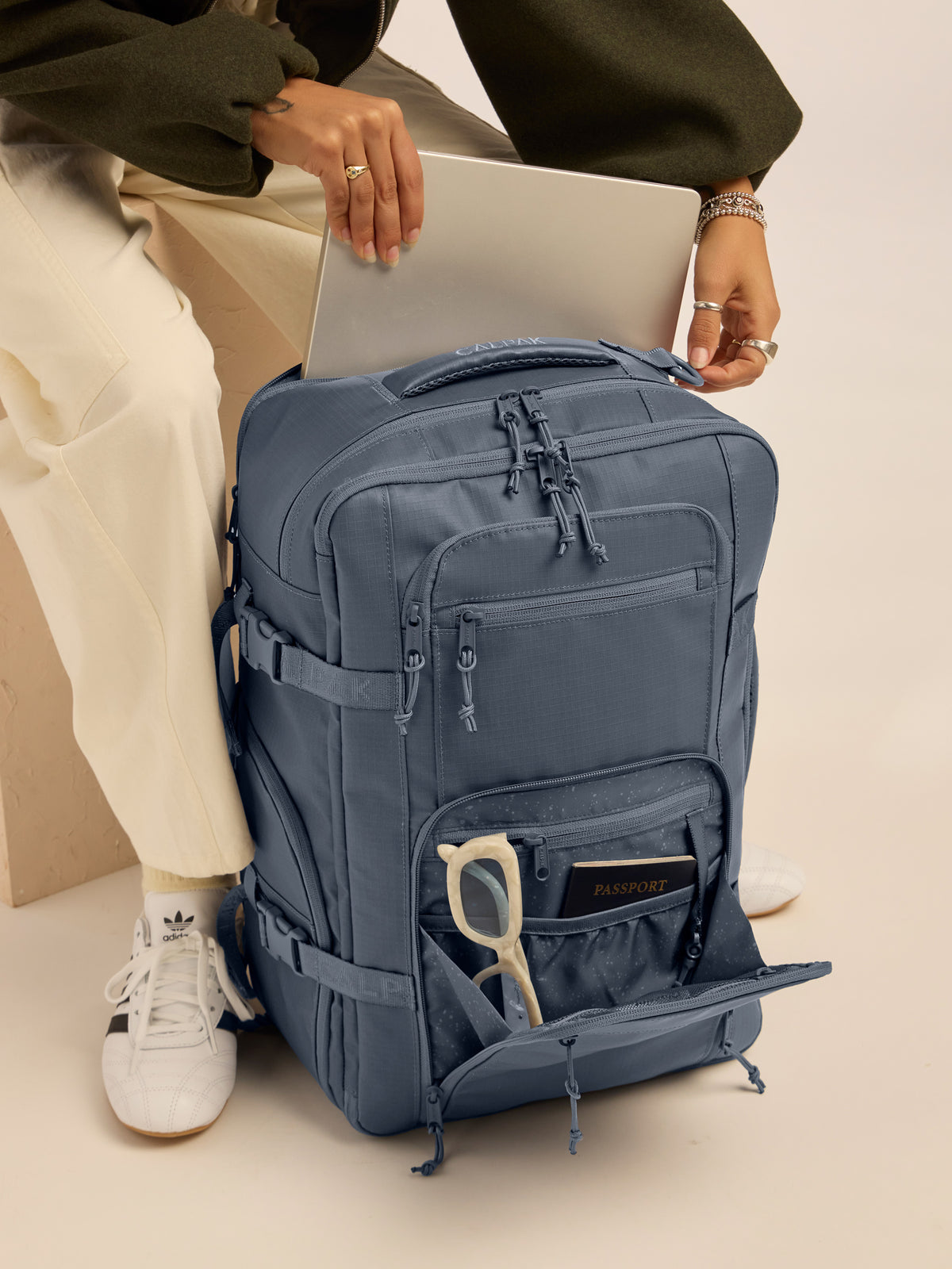 Model putting in laptop into the CALPAK Terra 26L Laptop Backpack Duffel in blue Matte Indigo; BPH2201-INDIGO
