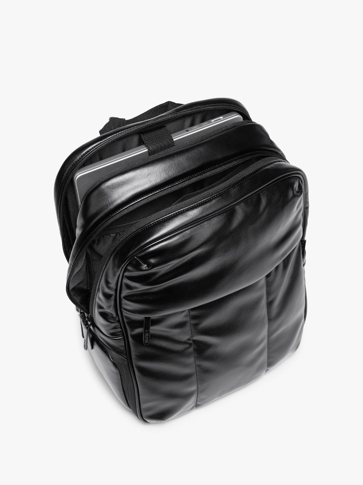 Laptop sleeve of Black CALPAK Luka 15 inch Laptop Backpack in vegan leather with a glossy finish, featuring a top carry handle, a main zippered compartment, and a front slip pocket, shown against a plain white background; BPL2001-BLACK-PU
