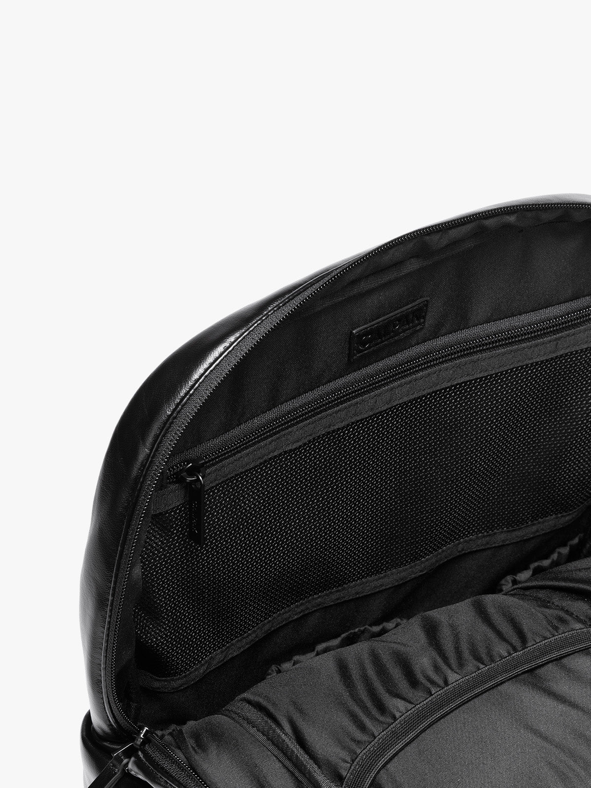 Inside zipper of CALPAK Luka 15 inch Laptop Backpack in vegan leather with a glossy finish, featuring a top carry handle, a main zippered compartment, and a front slip pocket, shown against a plain white background; BPL2001-BLACK-PU