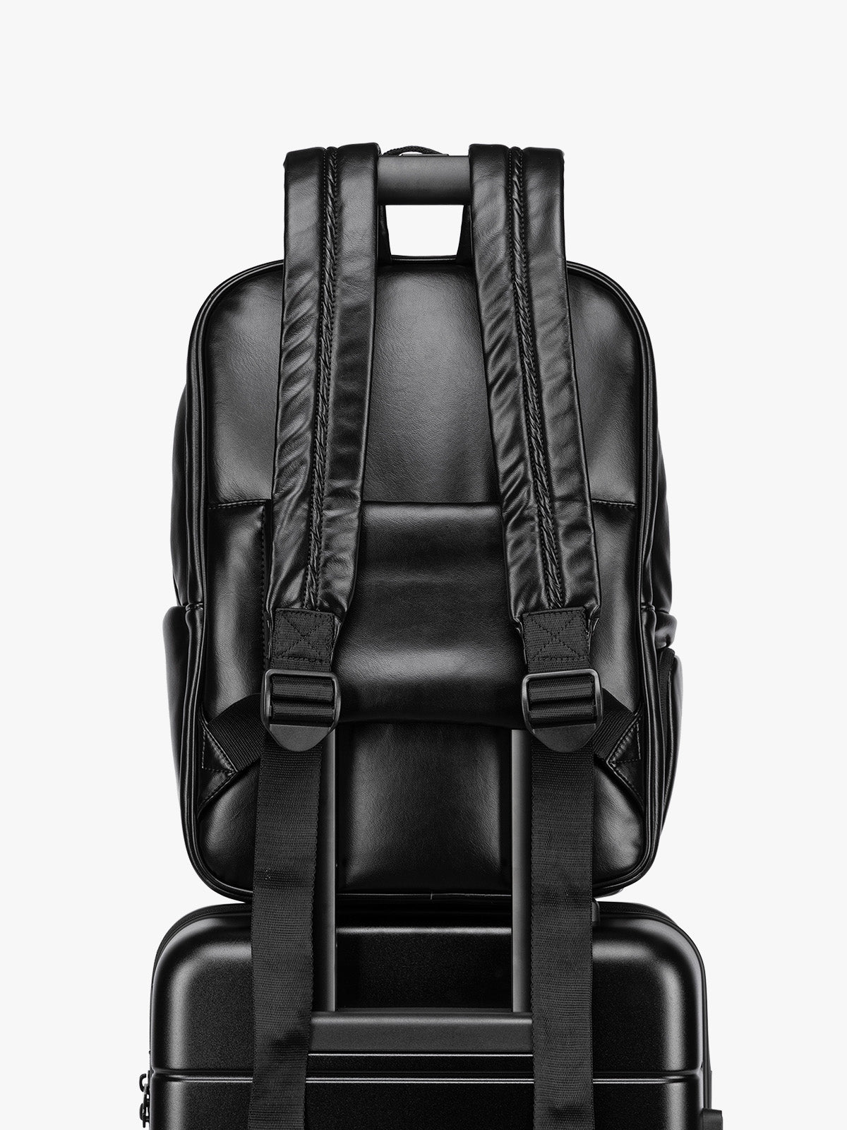 Backside luggage trolley sleeve of CALPAK Luka 15 inch Laptop Backpack in vegan leather with a glossy finish, featuring a top carry handle, a main zippered compartment, and a front slip pocket, shown against a plain white background; BPL2001-BLACK-PU