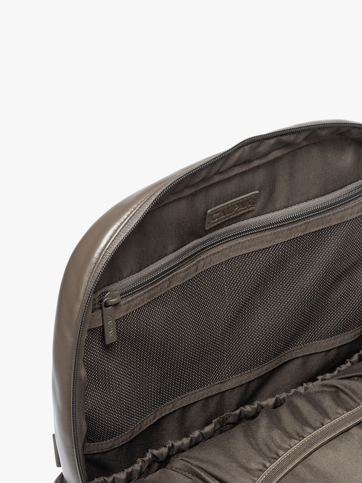Closeup of zipper inside the CALPAK Mushroom brown Luka 15 inch Laptop Backpack in vegan leather with a glossy finish, featuring a top carry handle, a main zippered compartment, and a front slip pocket, shown against a plain white background; BPL2001-MUSHROOM-PU