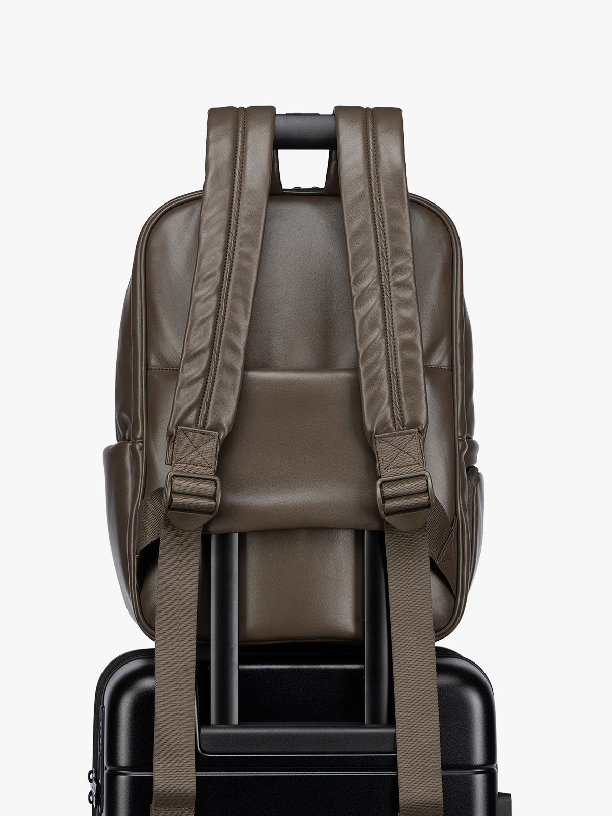 Backside luggage trolley sleeve of CALPAK Mushroom brown Luka 15 inch Laptop Backpack in vegan leather with a glossy finish, featuring a top carry handle, a main zippered compartment, and a front slip pocket, shown against a plain white background; BPL2001-MUSHROOM-PU