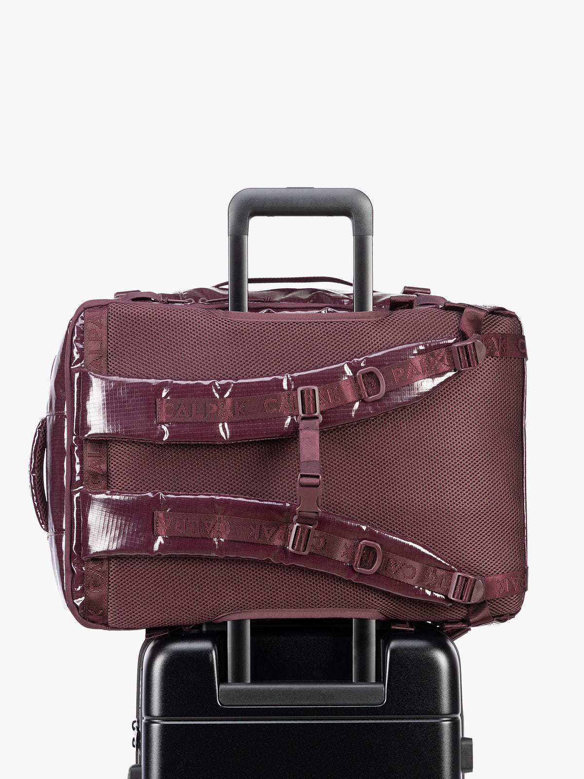 Back trolley sleeve of CALPAK Terra 35L Laptop Backpack Duffel in dark red Dark Cherry with tan accents on a white background; BPTL2601-DARK-CHERRY