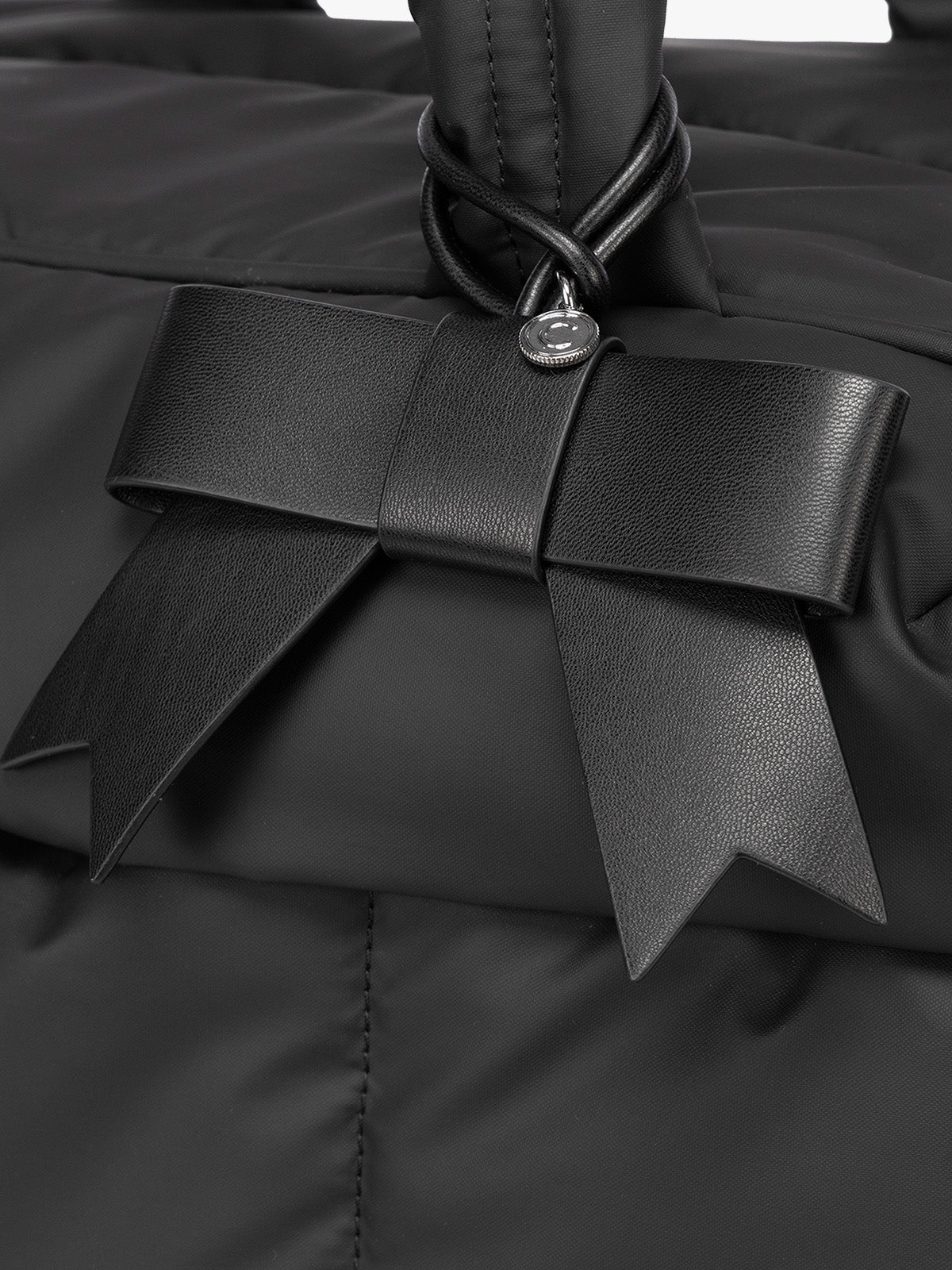Close-up of Black CALPAK Personalized Bow Bag Charm with a black strap and silver-tone metal ring at the top; BWBC2601-BLACK