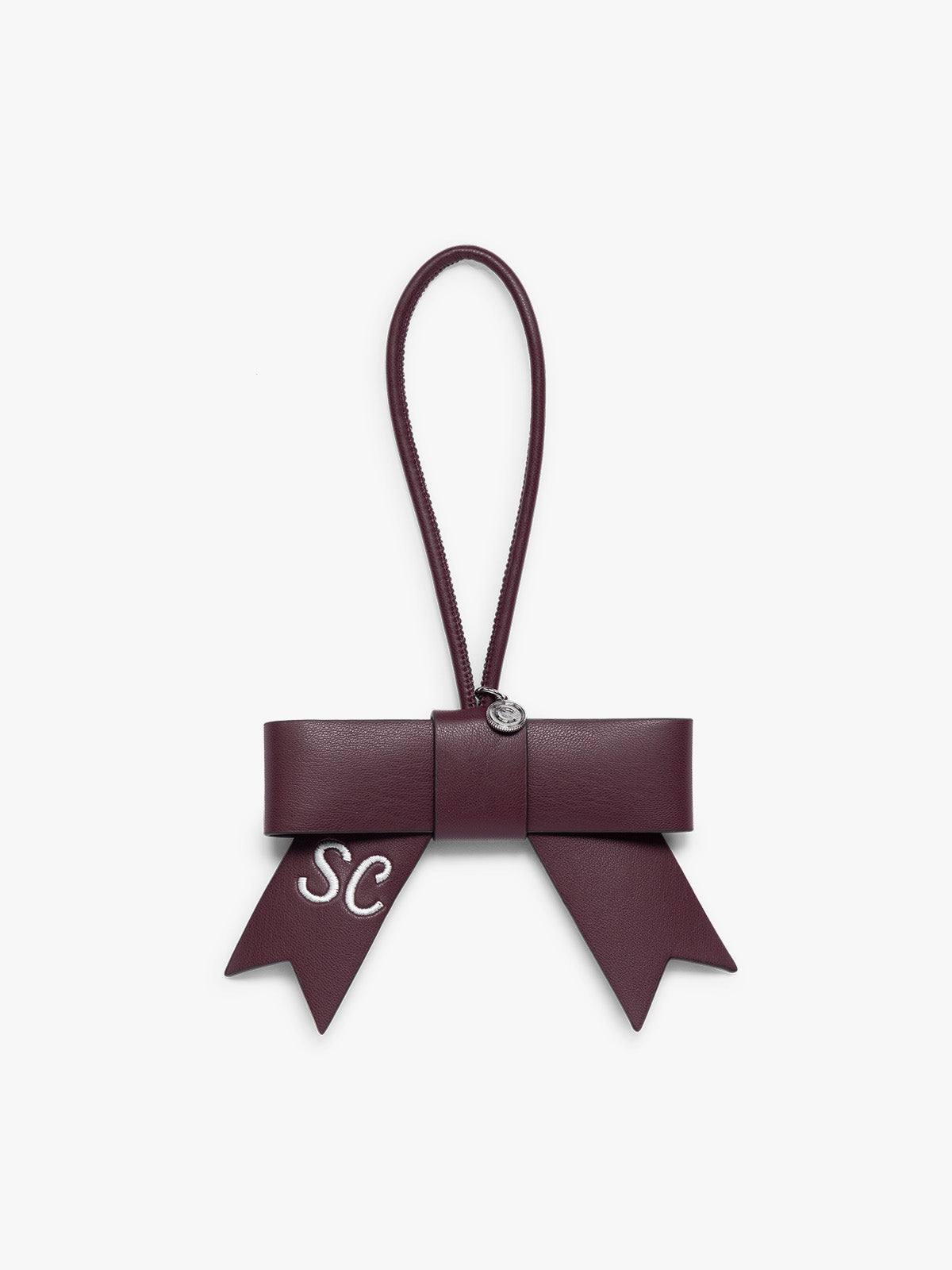 Burgundy Dark Cherry CALPAK Personalized Bow Bag Charm with a top loop, featuring a silver-tone metal ring and white embroidered initials 'SC' on one ribbon tail, set against a plain light gray background ; BWBC2601-DARK-CHERRY