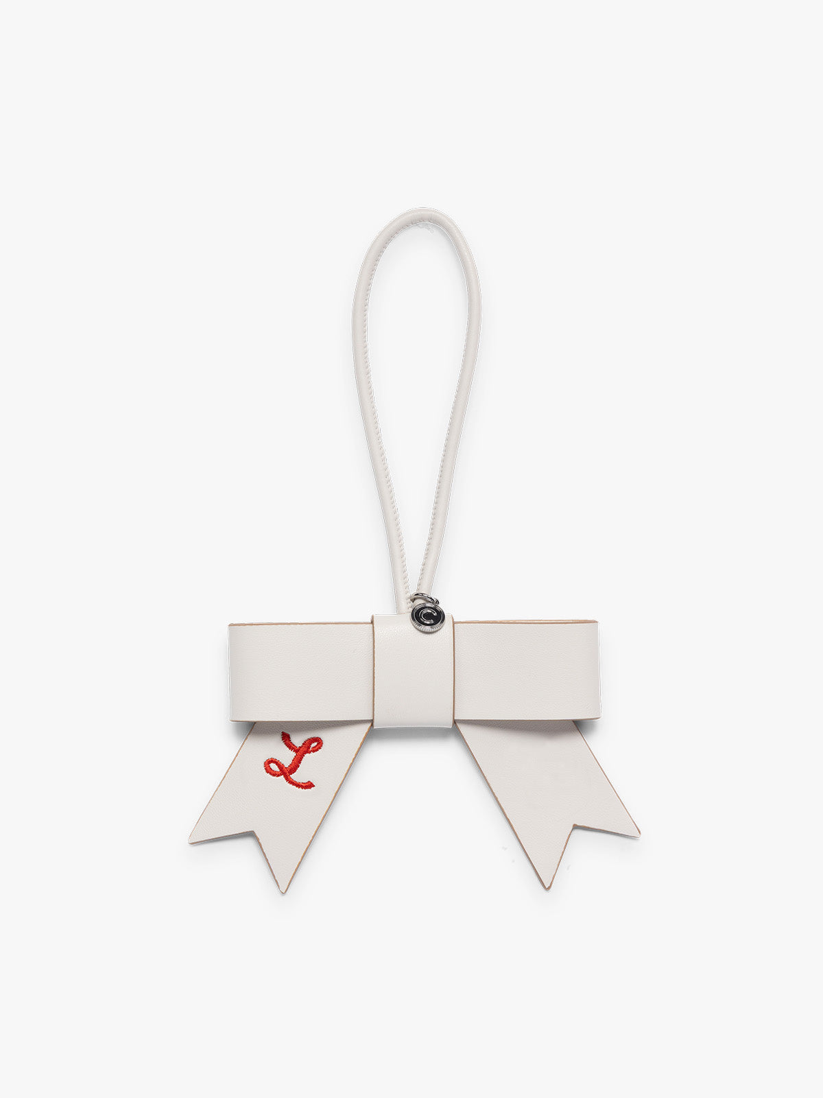 White Vanilla color CALPAK Personalized Bow Bag Charm with a top loop, featuring a silver-tone metal ring and red embroidered initials 'L' on both ribbon tail, set against a plain light gray background ; BWBC2601-VANILLA