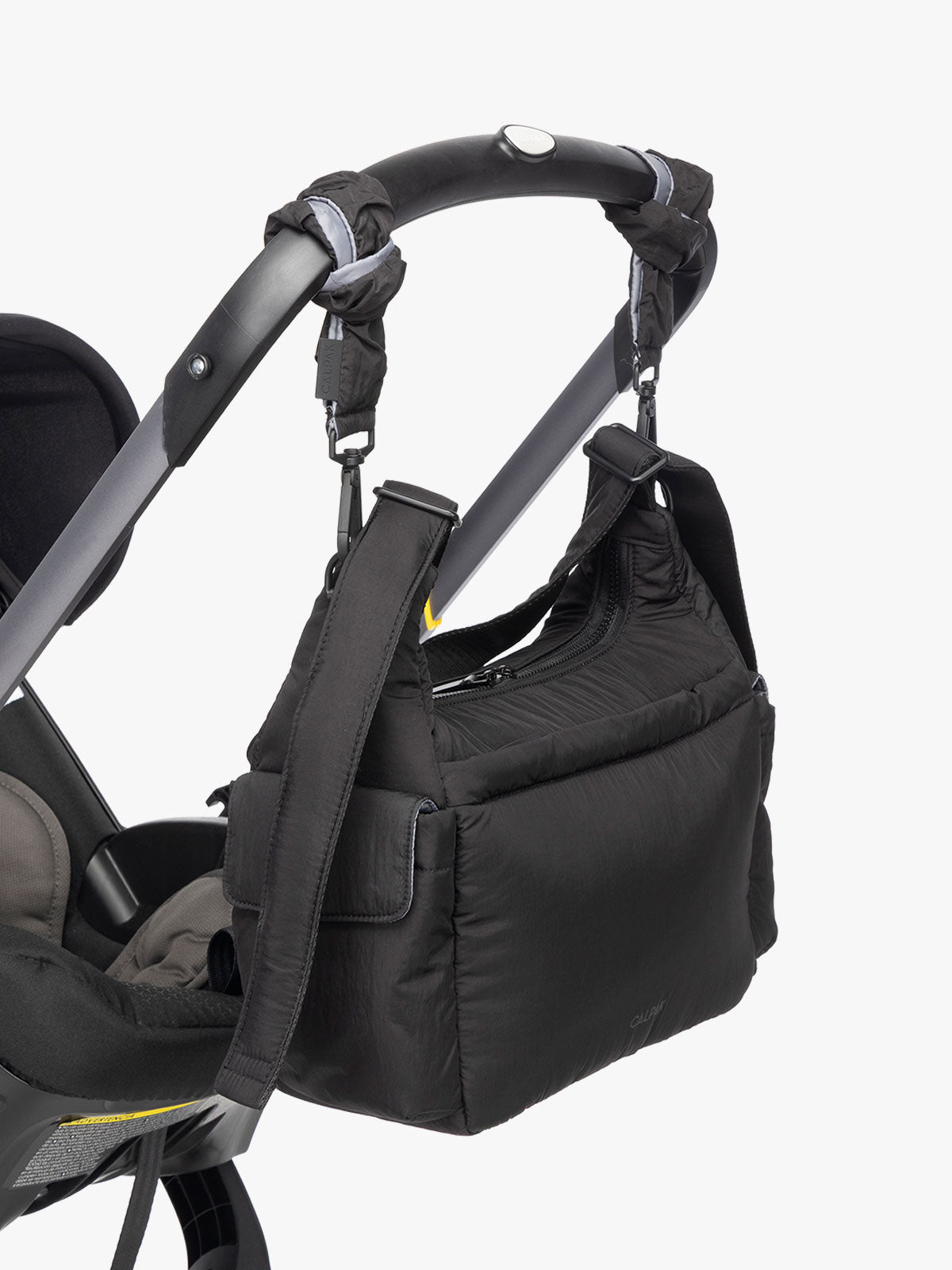 CALPAK Crossbody Diaper Bag in Black strapped on stroller with Stroller Straps; CDB2501-BLACK
