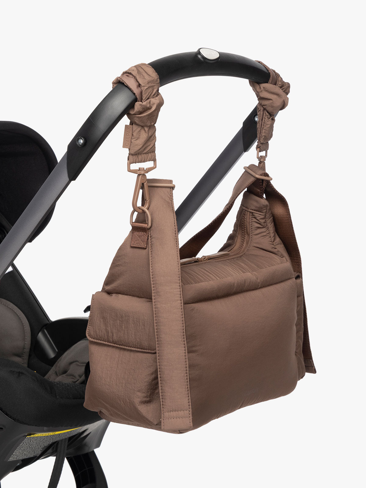 CALPAK Crossbody Diaper Bag in brown Hazelnut strapped on stroller with Stroller Straps; CDB2501-HAZELNUT