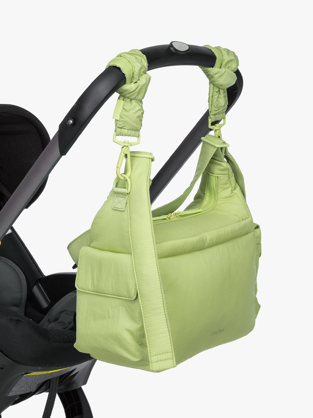CALPAK Crossbody Diaper Bag in light green Lime strapped on stroller with Stroller Straps; CDB2501-LIME