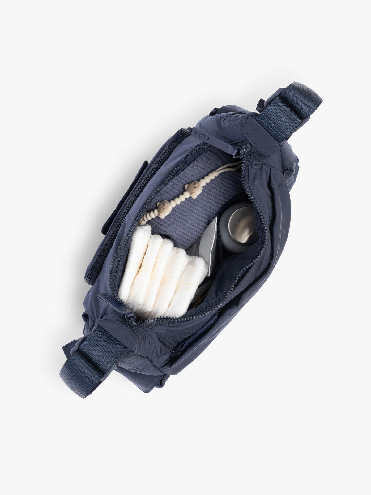 Top opened view with baby items in the CALPAK Crossbody Diaper Bag in blue Navy; CDB2501-NAVY