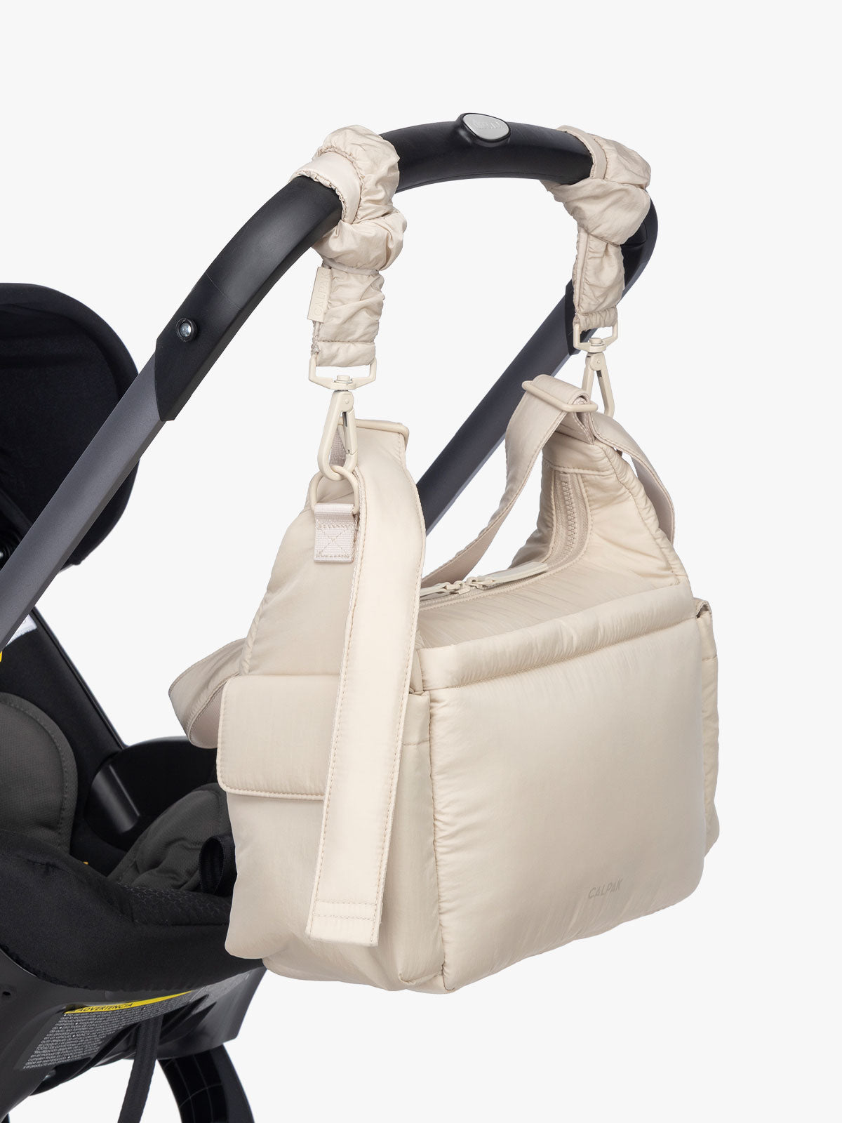 CALPAK Crossbody Diaper Bag in off-white Oatmeal strapped on stroller with Stroller Straps; CDB2501-OATMEAL