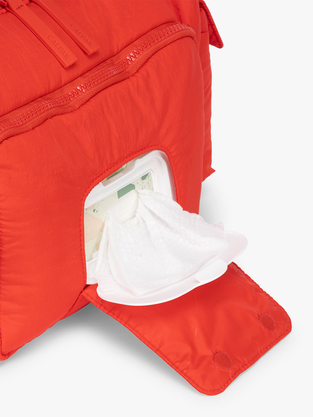 Front smart compartment for wipes in the CALPAK Crossbody Diaper Bag in red Tomato; CDB2501-TOMATO