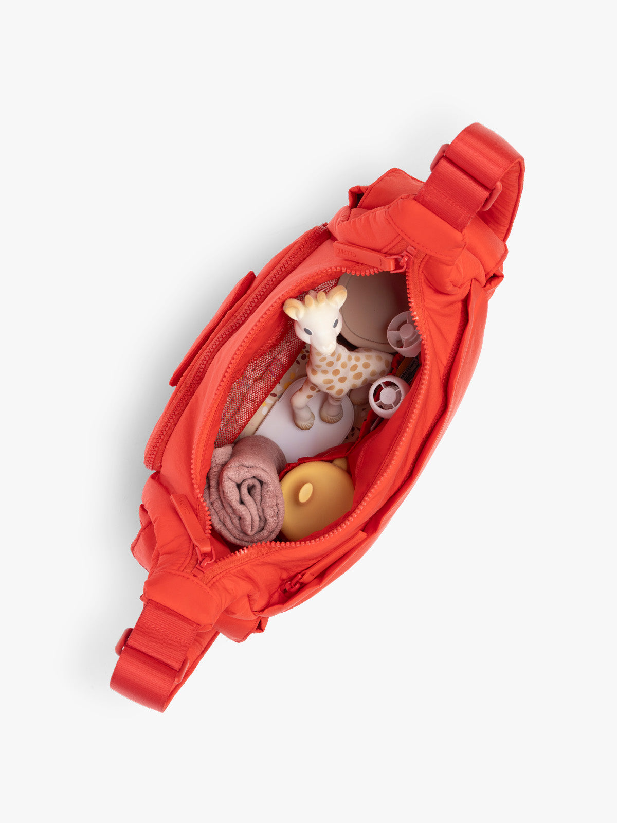 Top opened view with baby items inside CALPAK Crossbody Diaper Bag in red Tomato; CDB2501-TOMATO