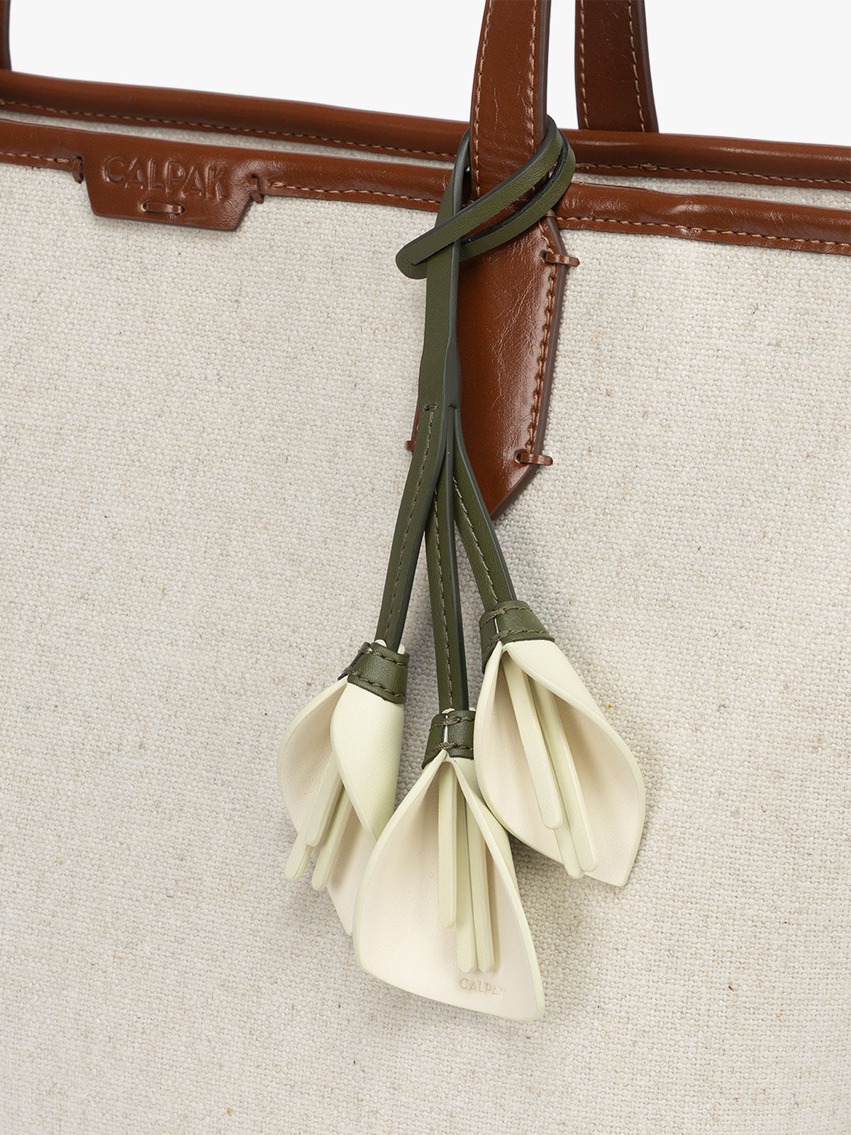 CALPAK Colette Calla Lilly Bag Charm with dark green strap and Celadon flower stem and white flower petals attached to a bag; CLBC2601-CELADON