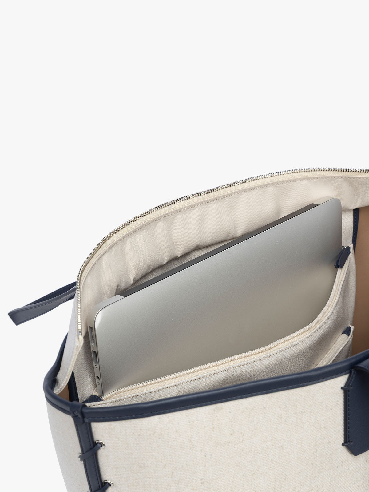 Laptop sleeve of CALPAK Colette 15" Canvas Laptop Tote with zipper and interior laptop sleeve in beige canvas material  with blue finishing in Natural Navy; CLCT2601-NATURAL-NAVY