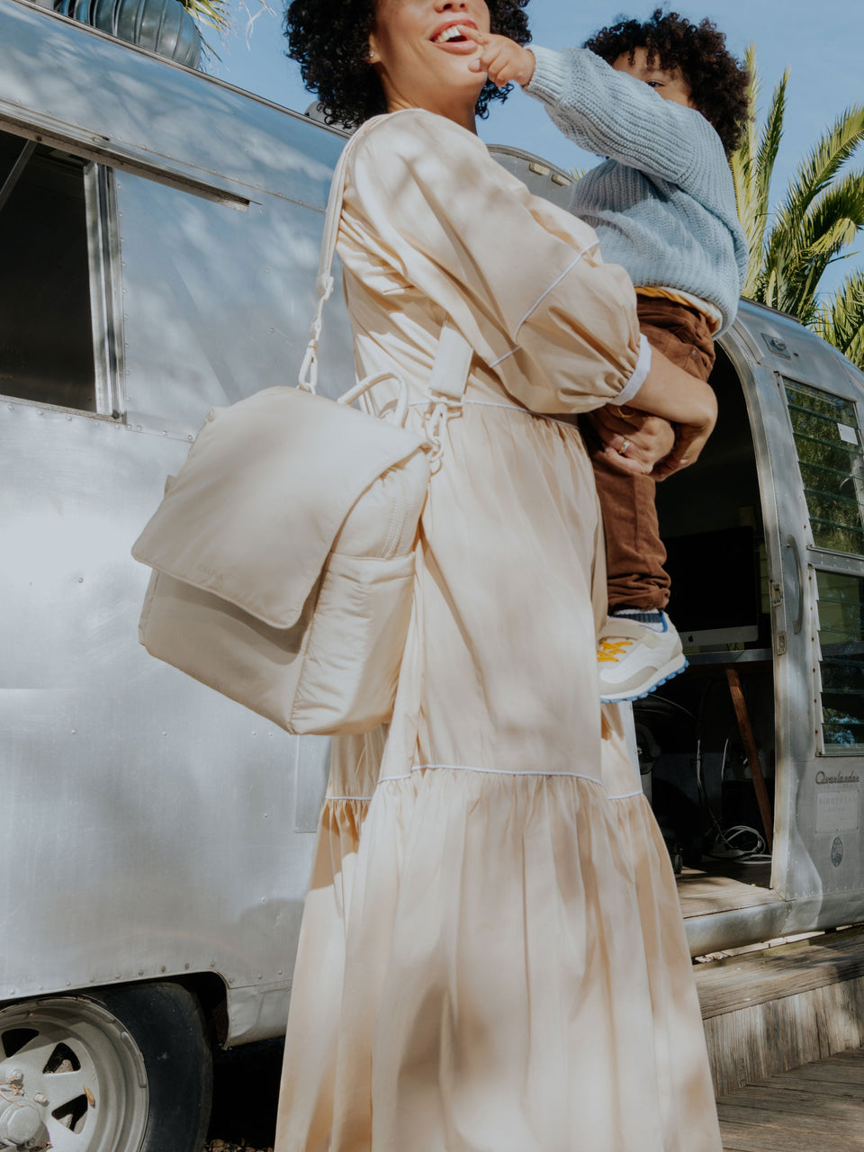 Model wearing CALPAK Convertible MIni Diaper Backpack as crossbody bag in oatmeal; BPC2401-OATMEAL, BBPC2401-OATMEAL