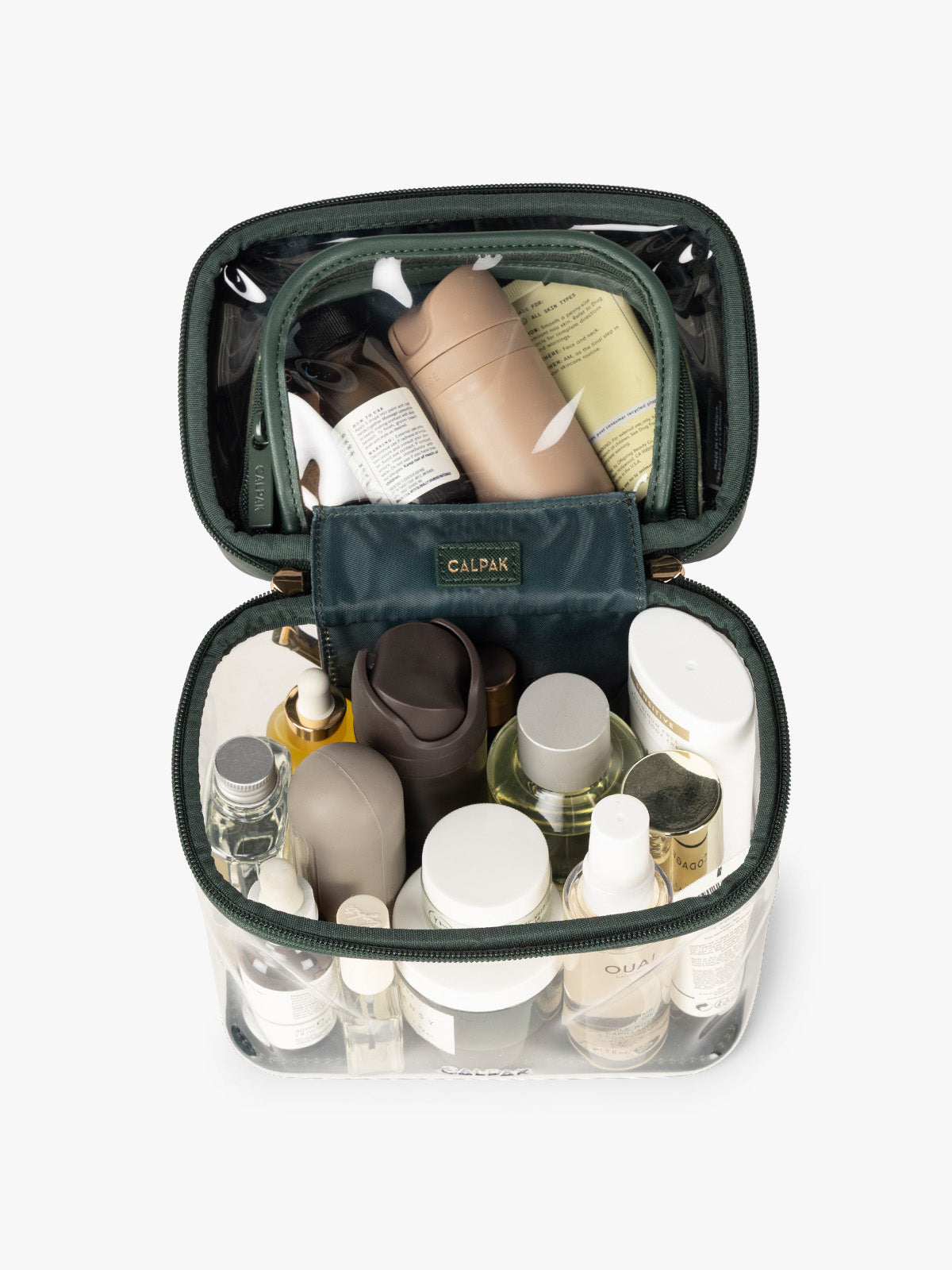 Makeup and toiletries in the CALPAK Clear Train Case in dark green Emerald; CTC2401-EMERALD