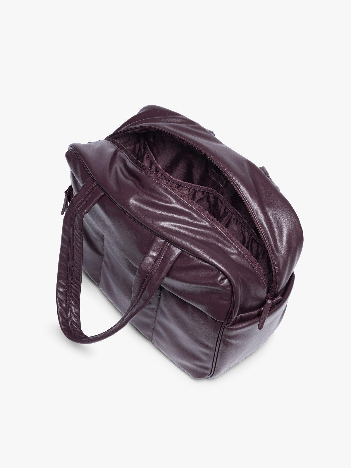Side view with zipper open showing inside of A dark burgundy CALPAK Luka Duffel in vegan leather with dual top handles and a front zippered pocket, photographed against a clean white background; DSM1901-DARK-CHERRY-PU