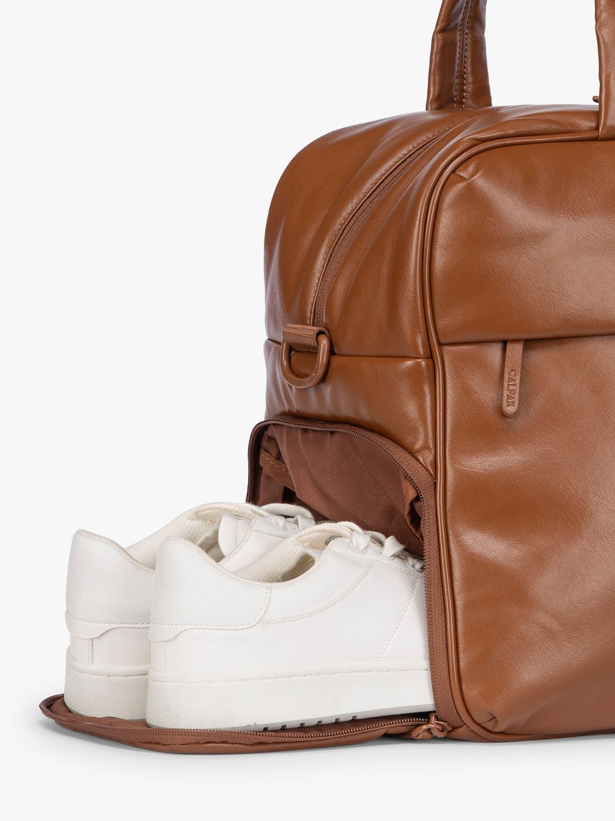 Side shoe compartment of Honey Brown CALPAK Luka Duffel in vegan leather with dual top handles and a front zippered pocket, photographed against a clean white background; DSM1901-HONEY-BROWN-PU