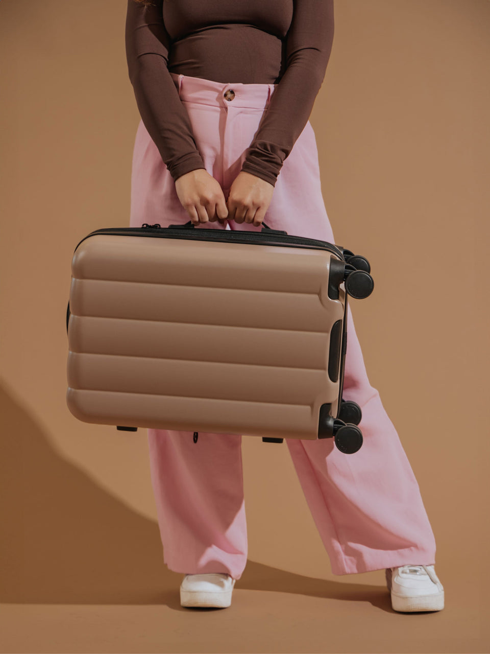 Model holding CALPAK Evry Carry-On Luggage by the side handle in brown; LCO1020-CHOCOLATE