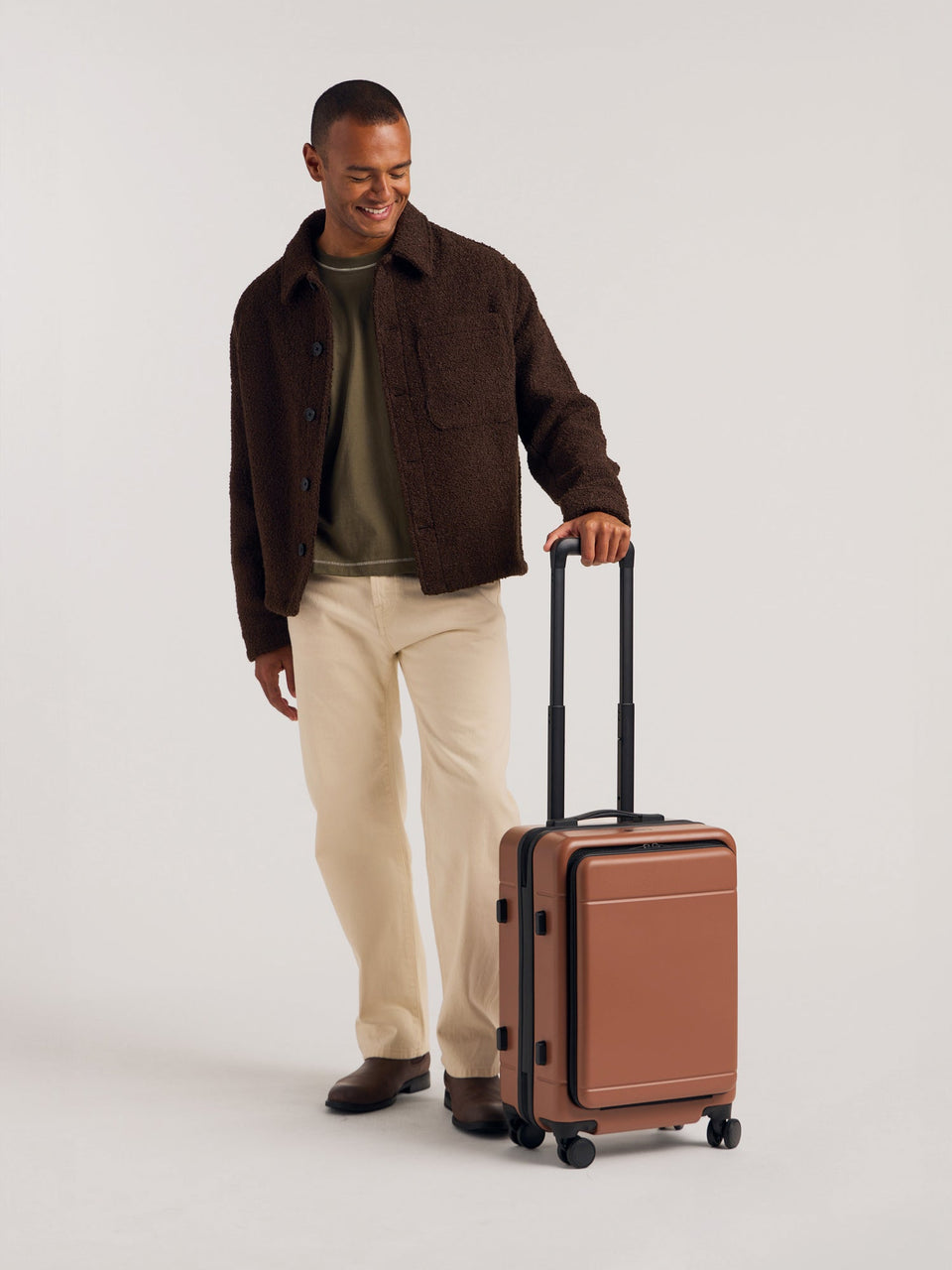 Model with CALPAK Hue Front Pocket Carry-On Luggage with hard shell carry-on spinner luggage with front-laptop compartment in Hazel; LHU1020-HAZEL