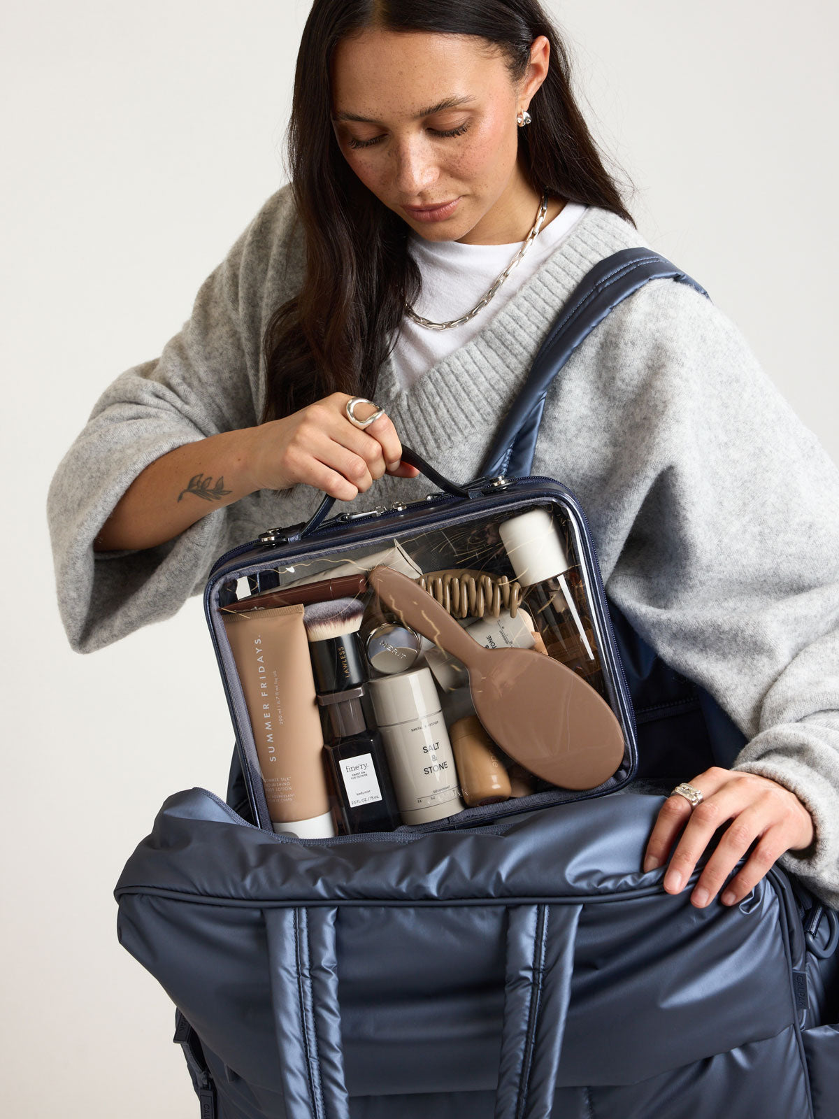 Person with CALPAK Clear Cosmetic Case in dark blue French Blue; CCC2001-METALLIC-INDIGO