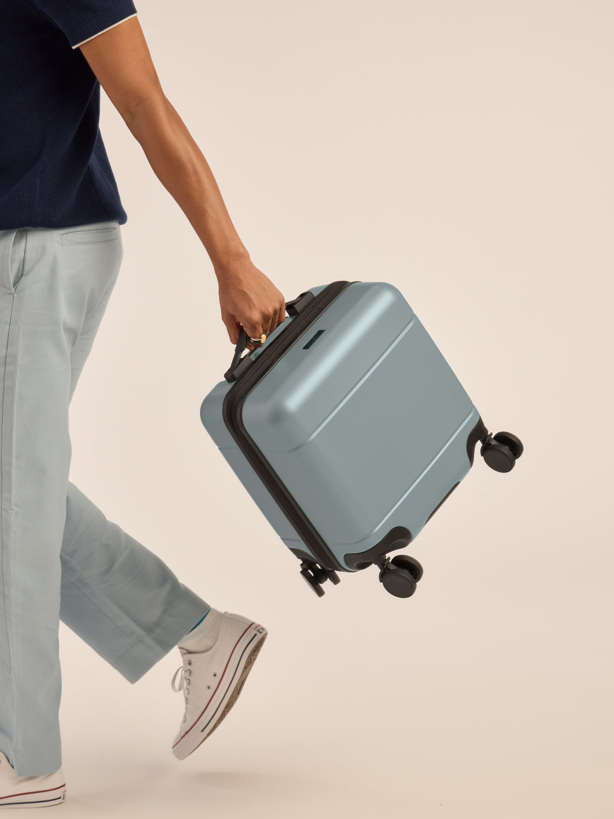 Model carrying the CALPAK Hue Mini Carry-On Luggage in blue Bluebell; LHU1014-BLUEBELL