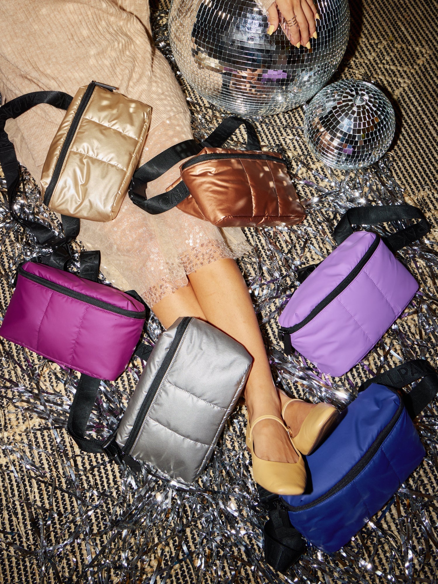 Model sitting besides CALPAK Luka Belt Bags in gold, copper, lilac, navy, gunmetal, and plum; BB1901-GUNMETAL