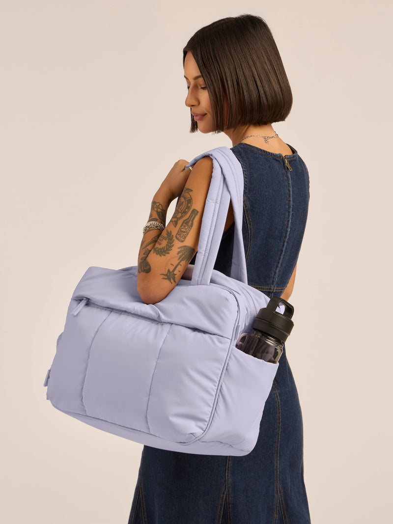 Model wearing CALPAK Luka Duffel in monochrome purple lavender Orchid with straps