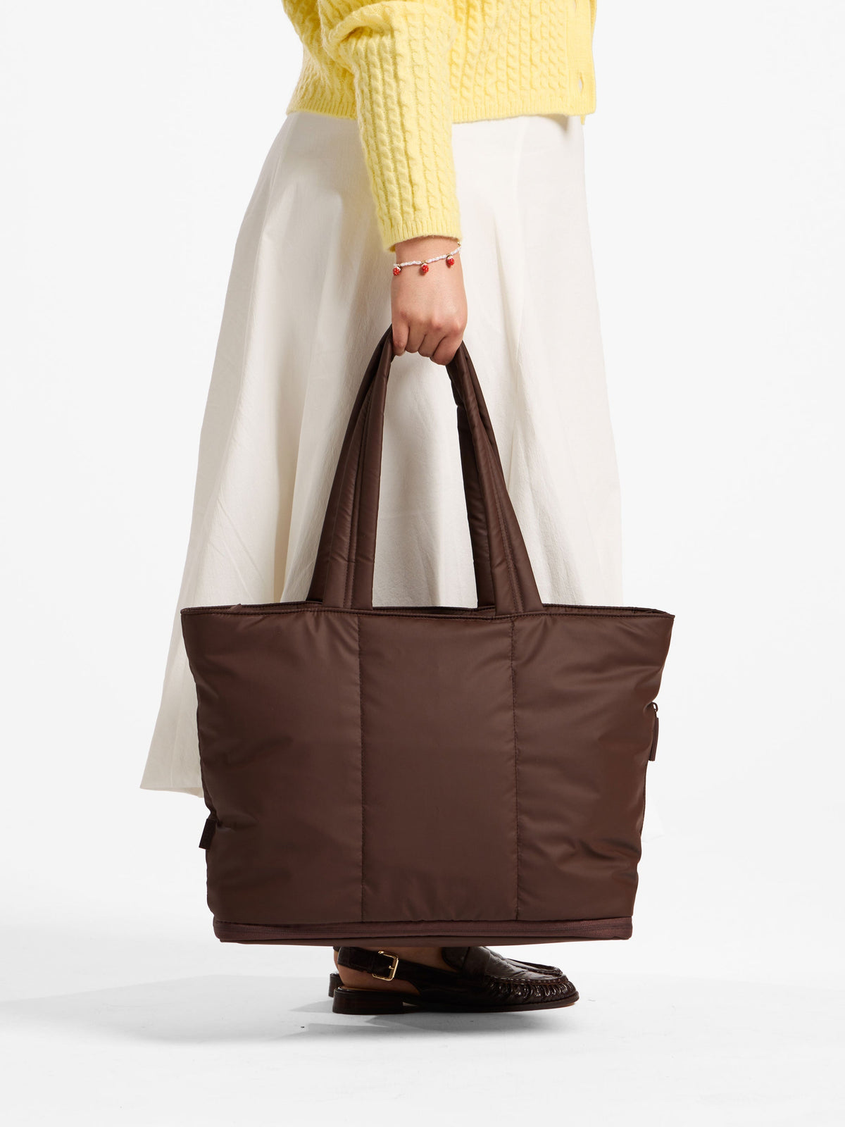 Model holds CALPAK Luka Expandable Laptop Tote Bag by handle in walnut; ALT2201-WALNUT