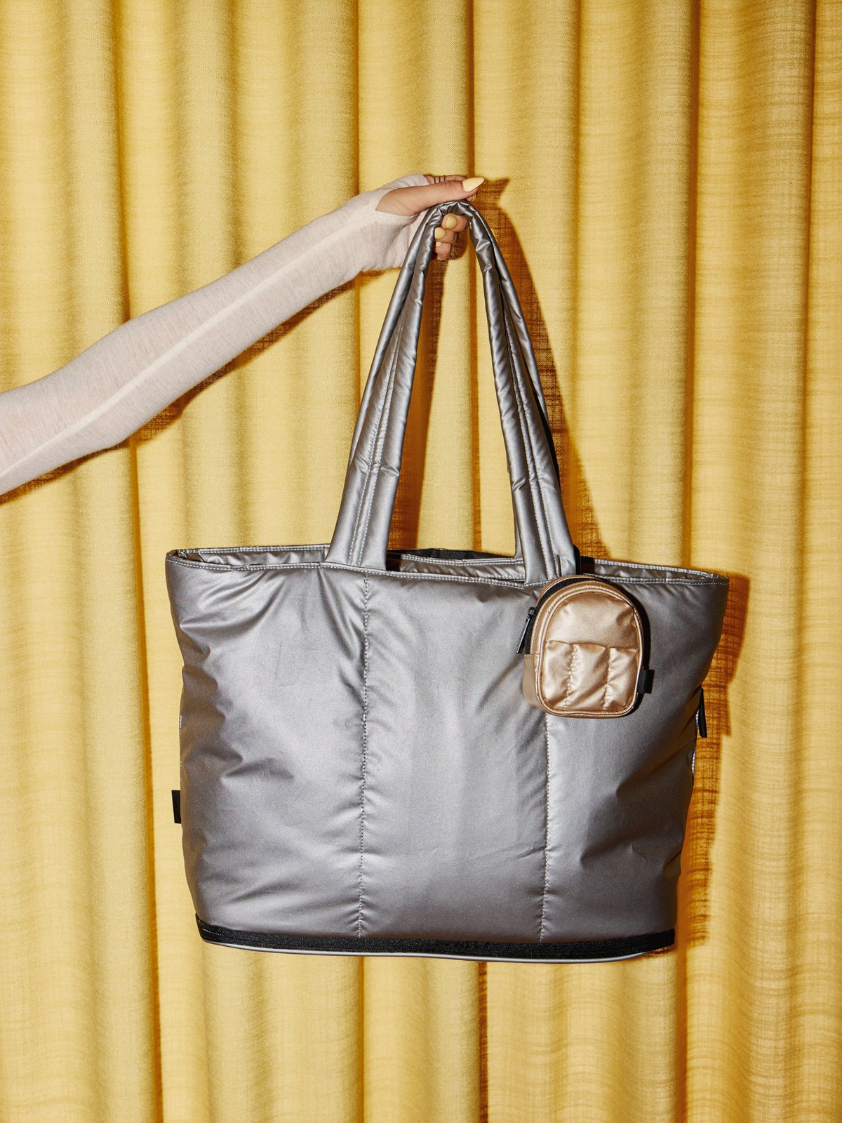 Model holding up Luka Expandable Laptop Tote in gunmetal with Luke Key Pouch clipped on strap; ALT2201-GUNMETAL