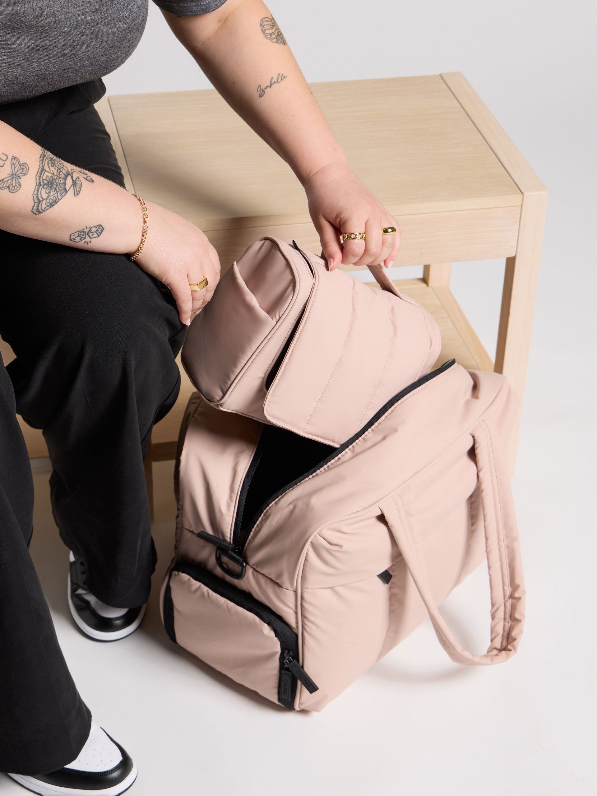 Model placing rose quartz pink luka hanging toiletry bag inside best-selling luka duffel; TLH2301-ROSE-QUARTZ