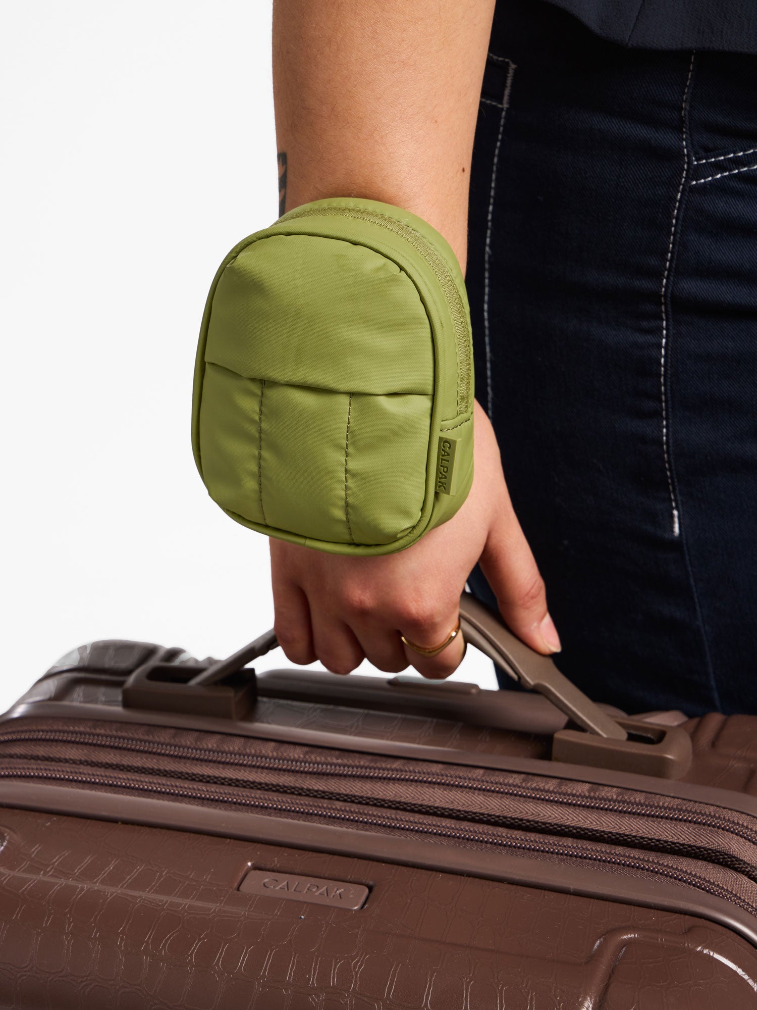 Model wearing pistachio CALPAK Luka Key Pouch around wrist; AMB2201-PISTACHIO