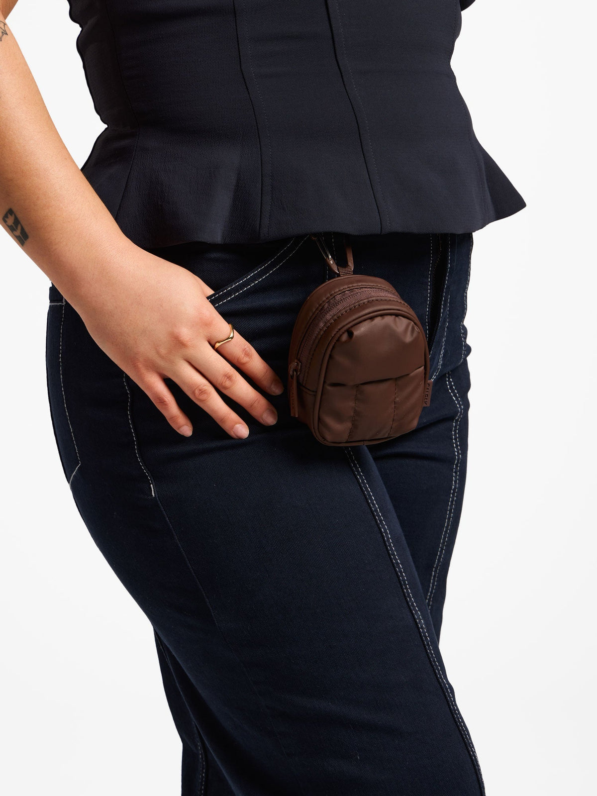 Model wearing walnut CALPAK Luka Key Pouch attached to belt loop by carabiner clip; AMB2201-WALNUT